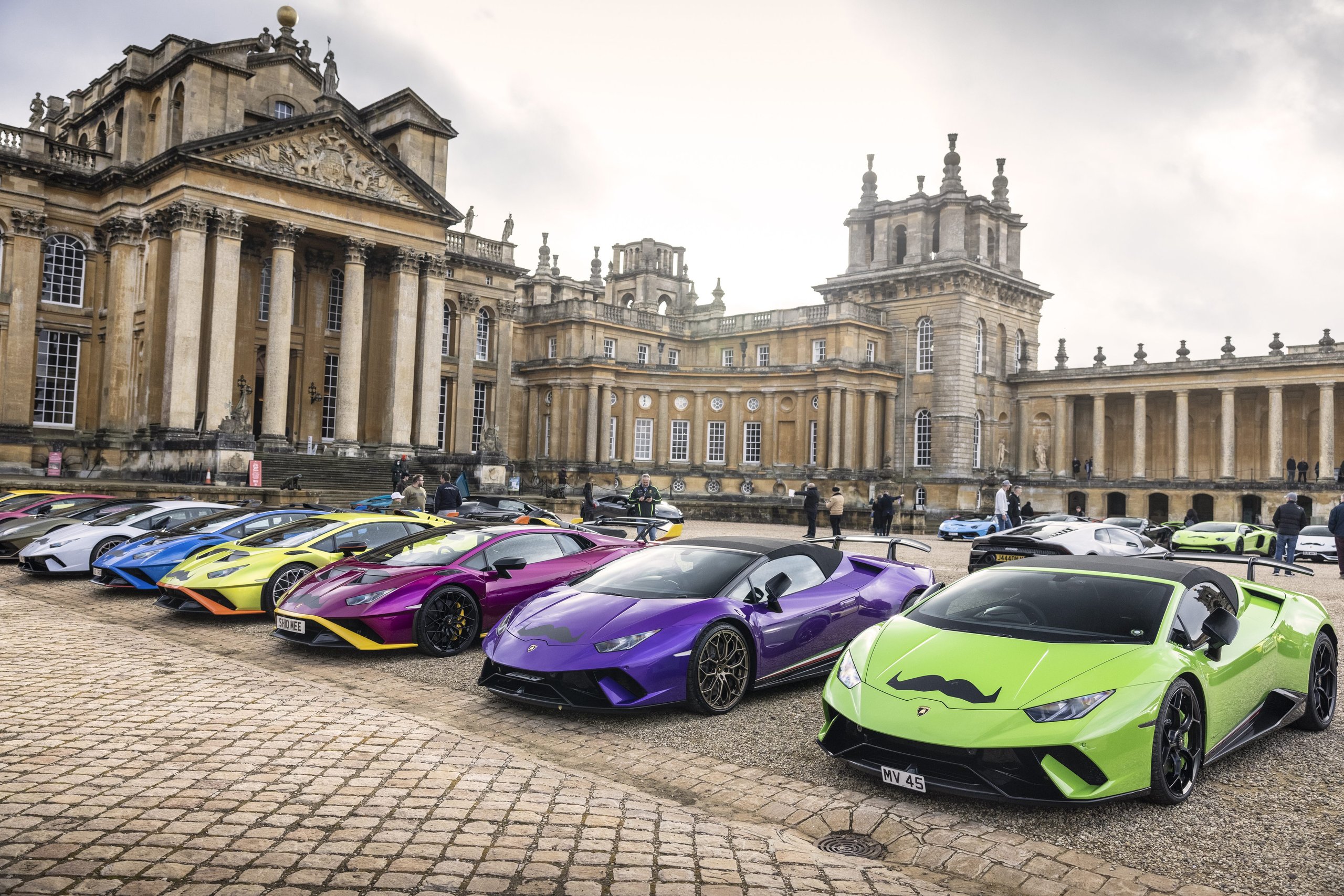 Lamborghini'S Global Movember Bull Run Turned 200 Supercars Into Rolling Billboards For Men'S Health 7 Line of colorful lamborghini huracán models with movember mustache decals parked on cobblestone at blenheim palace