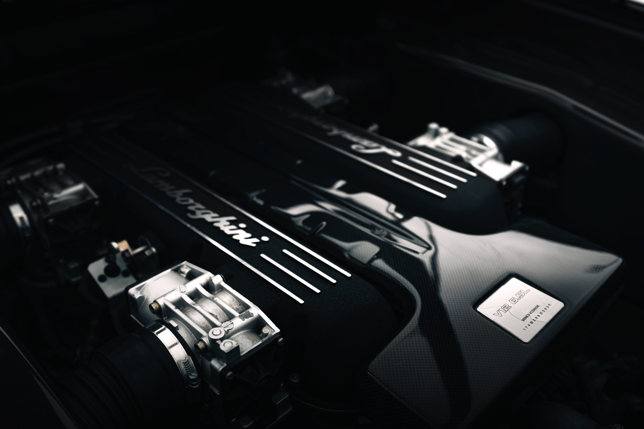 The Murciélago Was Lamborghini'S Last V12 You Could Row Yourself, And That Changes Everything About How We Remember It 5 Close-up of the lamborghini murciélago v12 engine bay showing carbon fiber cover and 6. 5l badge