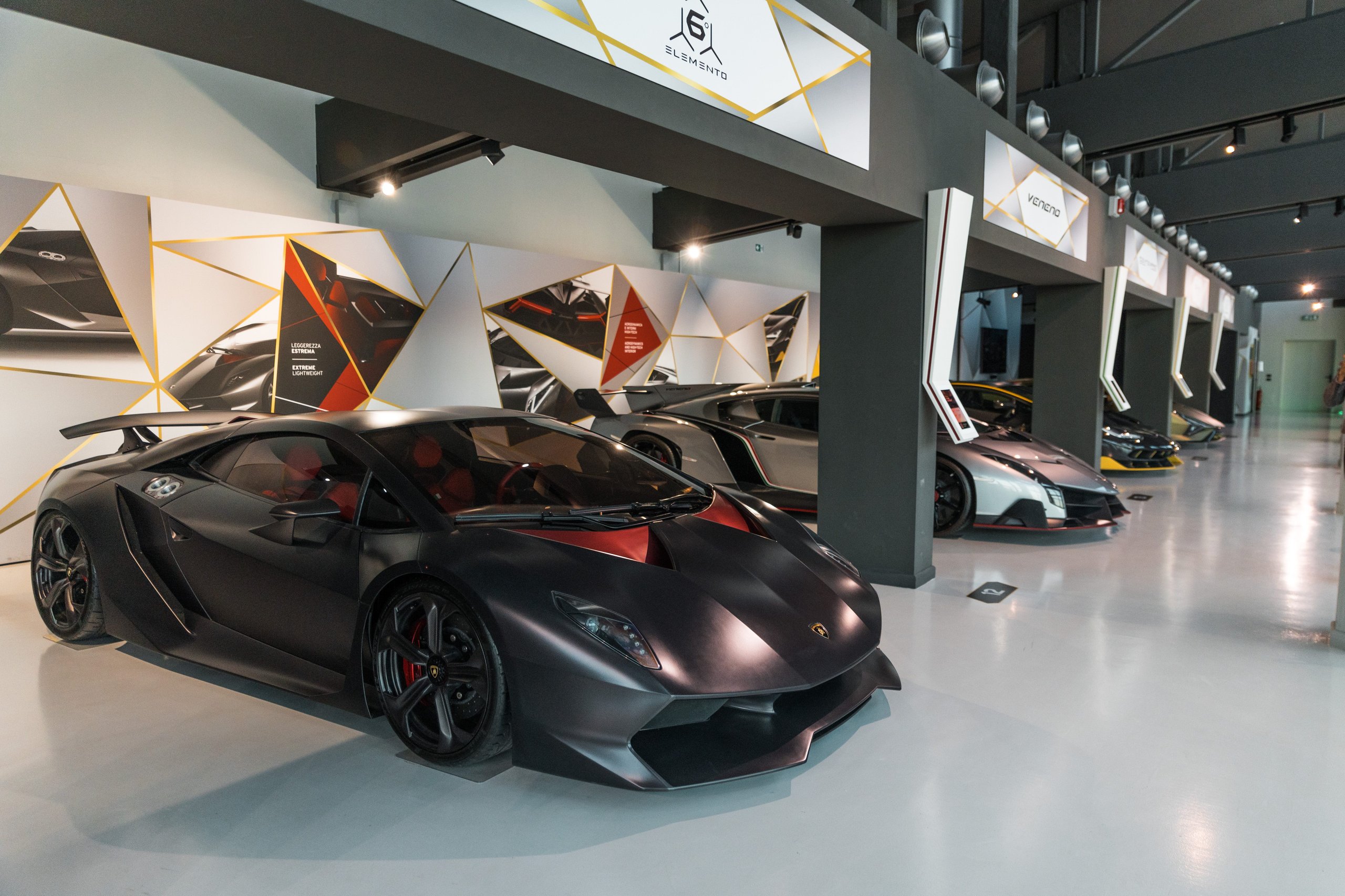 Line of lamborghini limited-edition and concept cars including the sesto elemento and veneno displayed in the museum with geometric wall graphics
