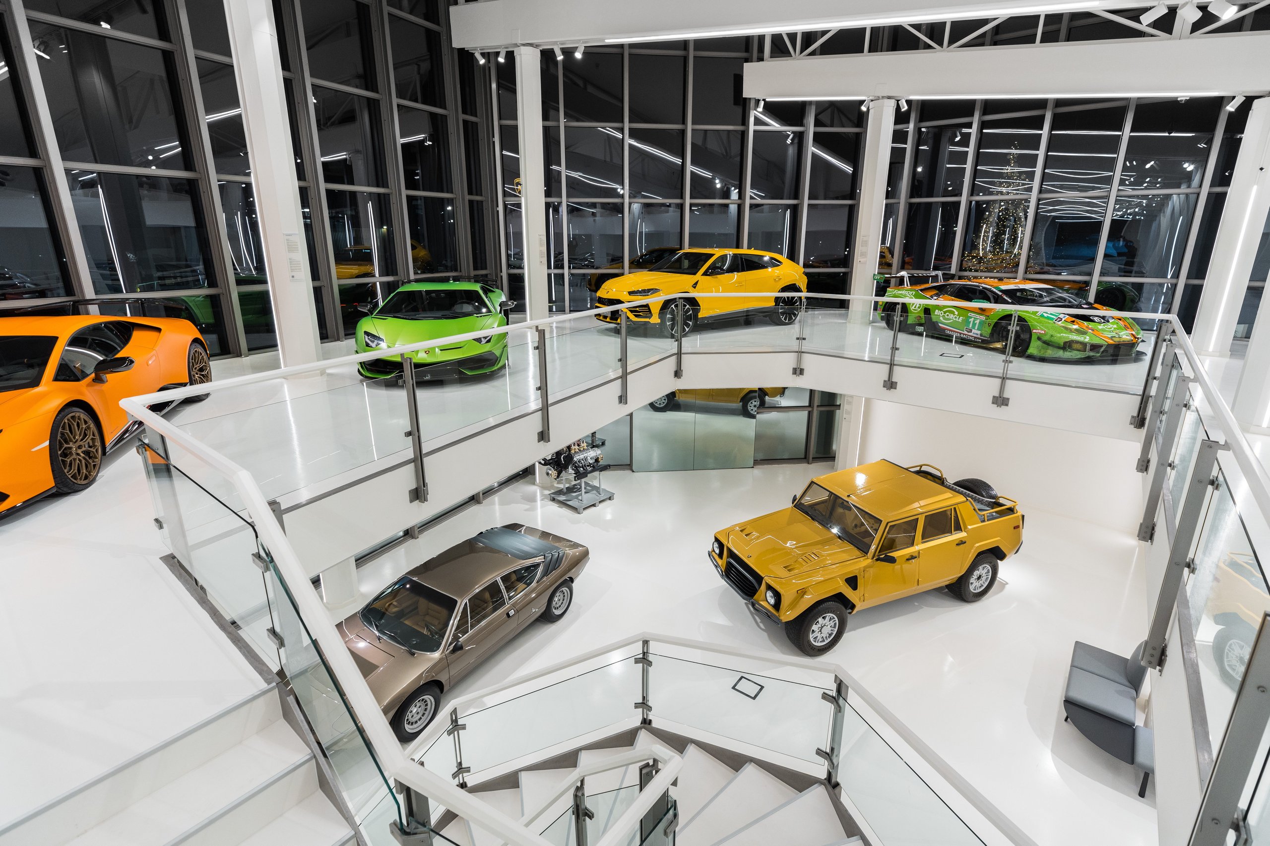 Elevated view of the redesigned automobili lamborghini museum showing multiple levels with a yellow urus, green huracán, and classic lm002 on display