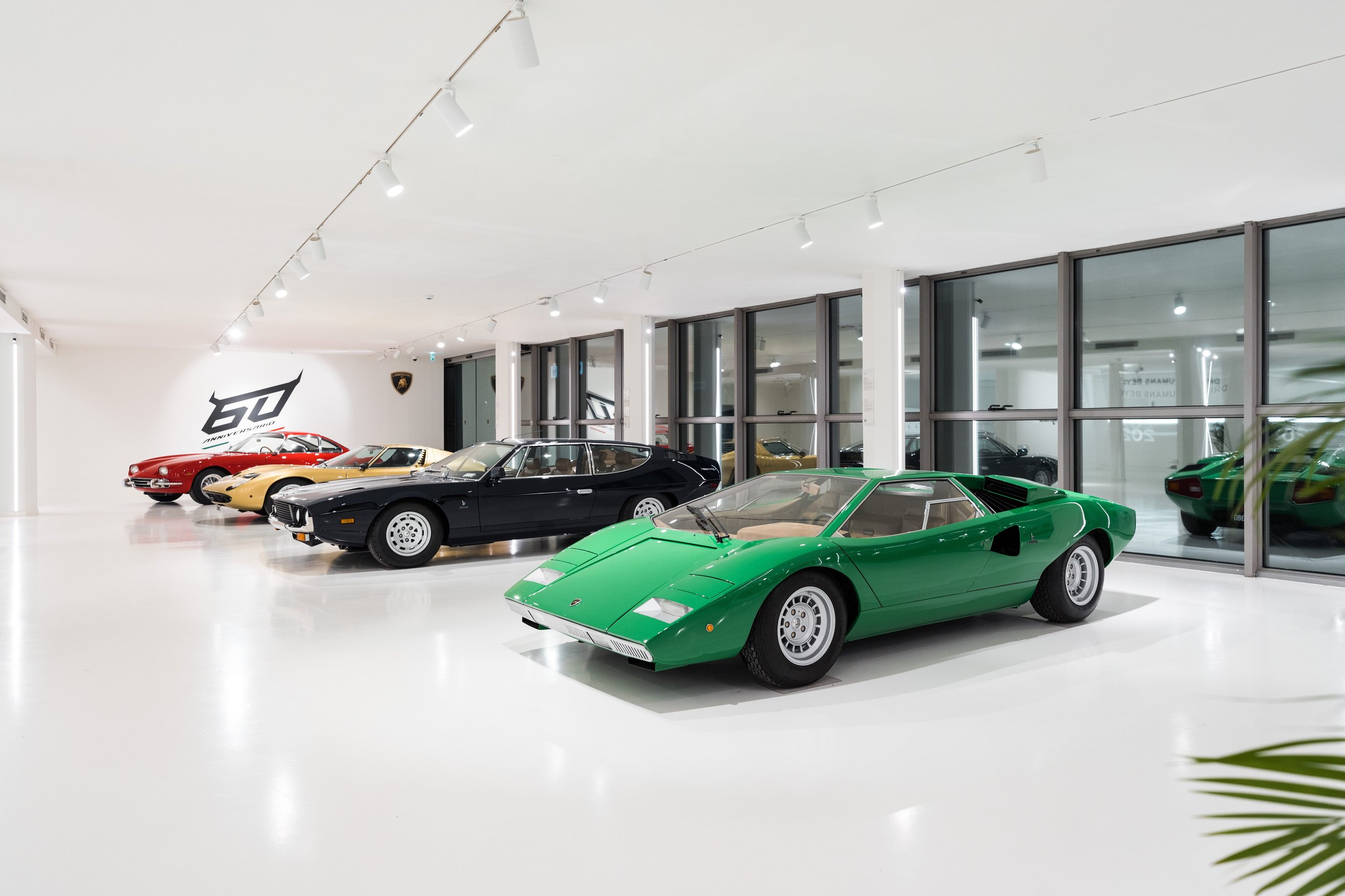 Line of classic lamborghini heritage models including a green countach, black espada, yellow miura, and red 350 gt in the redesigned museum