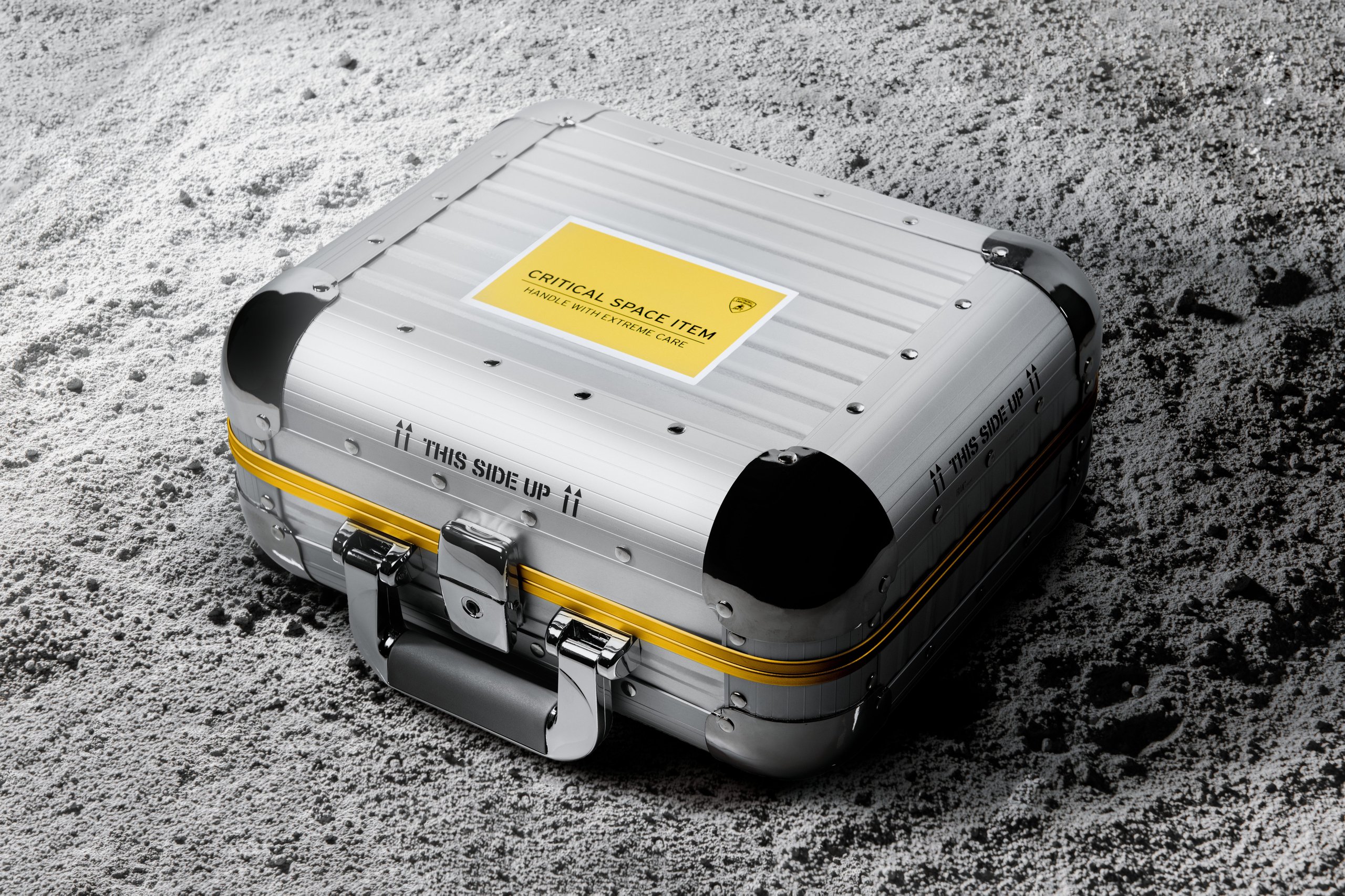 Lamborghini'S Space Key Nft Pairs Iss-Flown Carbon Fiber With Digital Art In A Five-Unit Collector'S Gambit 5 Closed silver and yellow protective case labeled critical space item on a lunar-like surface