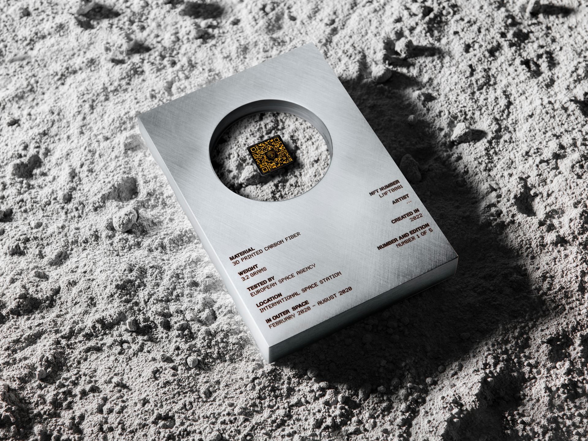 Lamborghini'S Space Key Nft Pairs Iss-Flown Carbon Fiber With Digital Art In A Five-Unit Collector'S Gambit 9 Top-down close-up of the lamborghini space key nft display with qr code on a lunar regolith surface