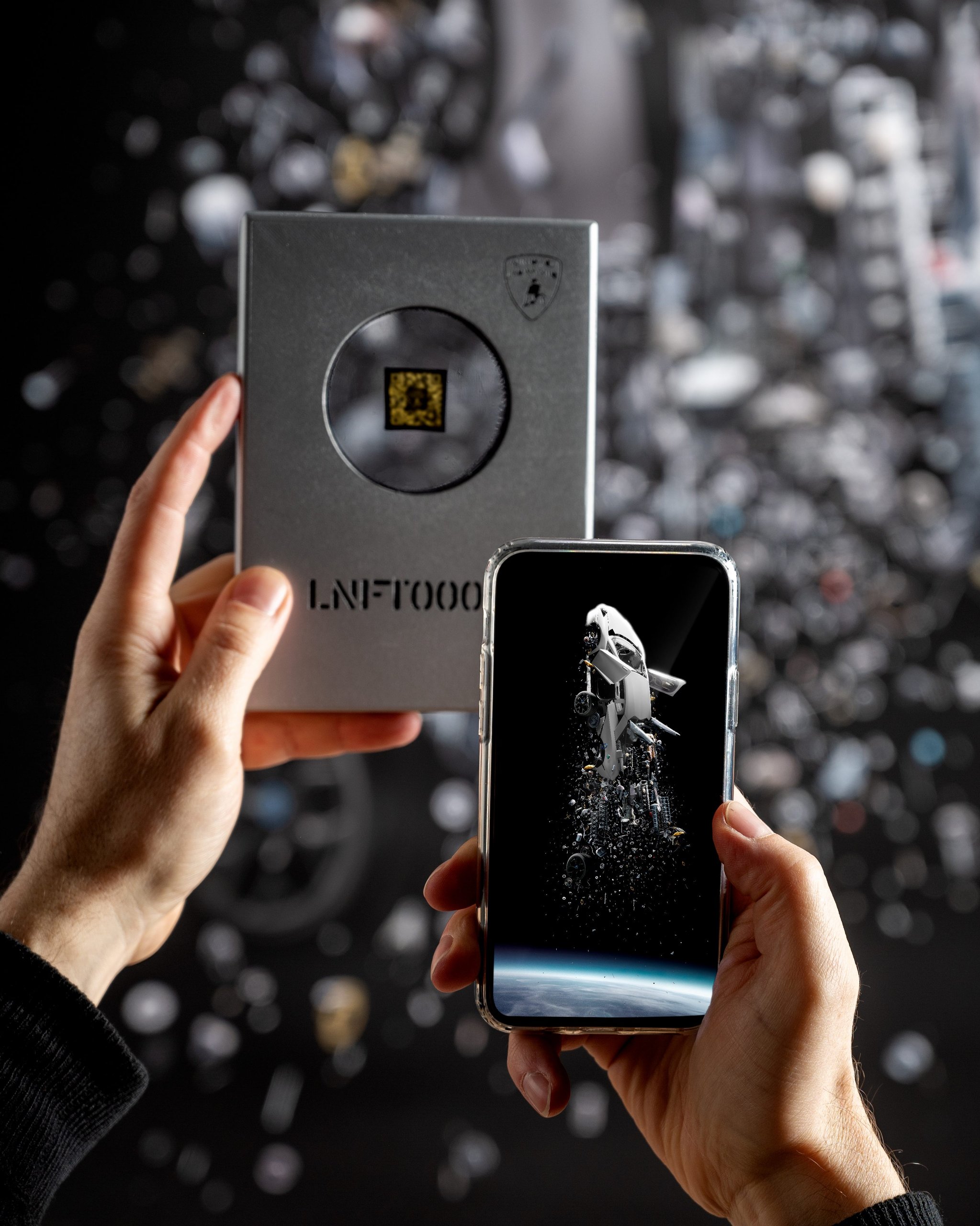 Lamborghini'S 'Space Time Memory' Nft Pairs Iss Carbon Fiber With 600-Million-Pixel Art Of An Exploding Ultimae 7 Hands holding the lamborghini space key silver box alongside a smartphone displaying the space time memory digital artwork