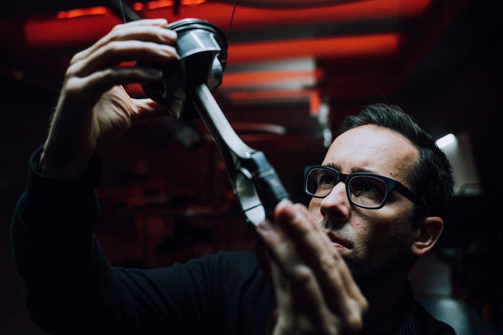 Artist Fabian Oefner examines a piston and connecting rod assembly under red lighting during the creation of Lamborghini's Space Time Memory NFT project