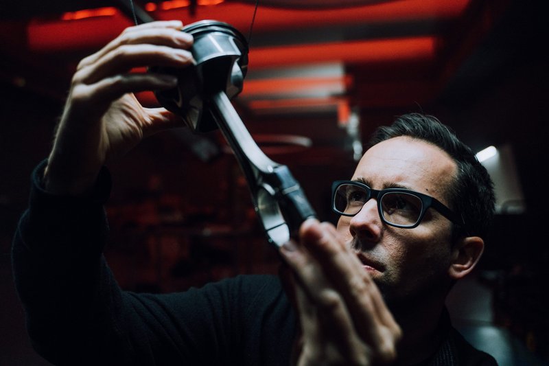 Artist Fabian Oefner examines a piston and connecting rod assembly under red lighting during the creation of Lamborghini's Space Time Memory NFT project
