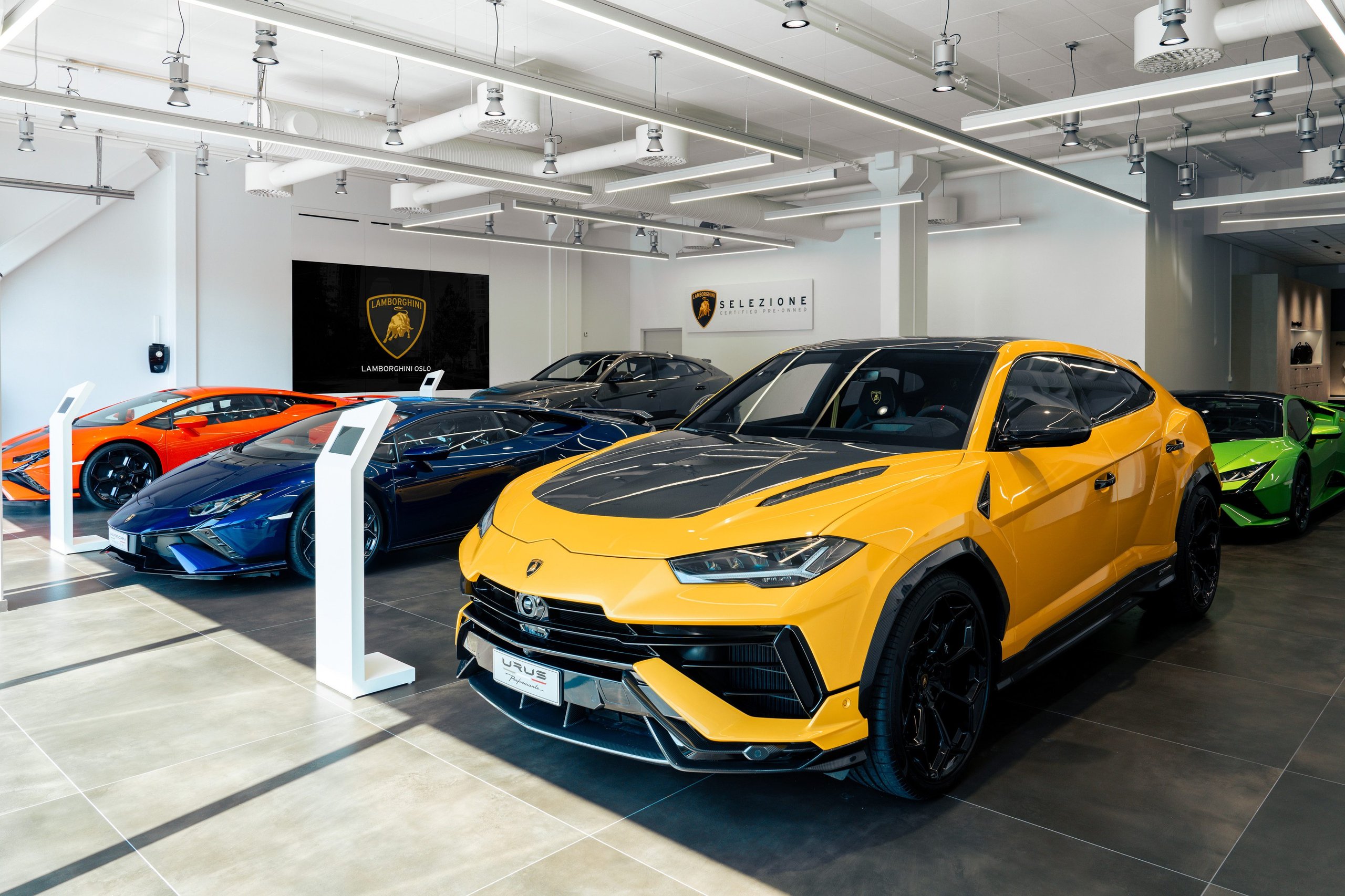 Lamborghini Oslo: Why Norway'S First Showroom Paired A V12 Hybrid Flagship With Frank Sinatra'S Miura 9 Yellow lamborghini urus displayed in the oslo showroom alongside a blue huracán and orange aventador