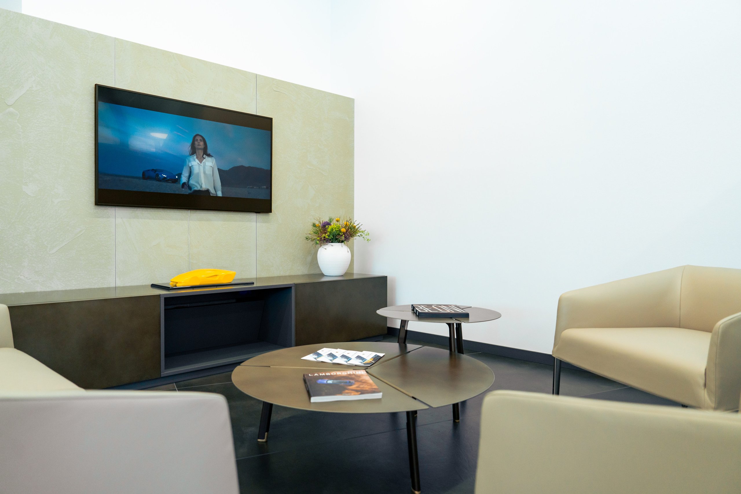Lamborghini Oslo: Why Norway'S First Showroom Paired A V12 Hybrid Flagship With Frank Sinatra'S Miura 7 Modern lamborghini dealership client lounge with leather seating, coffee tables, magazines, and a large display screen