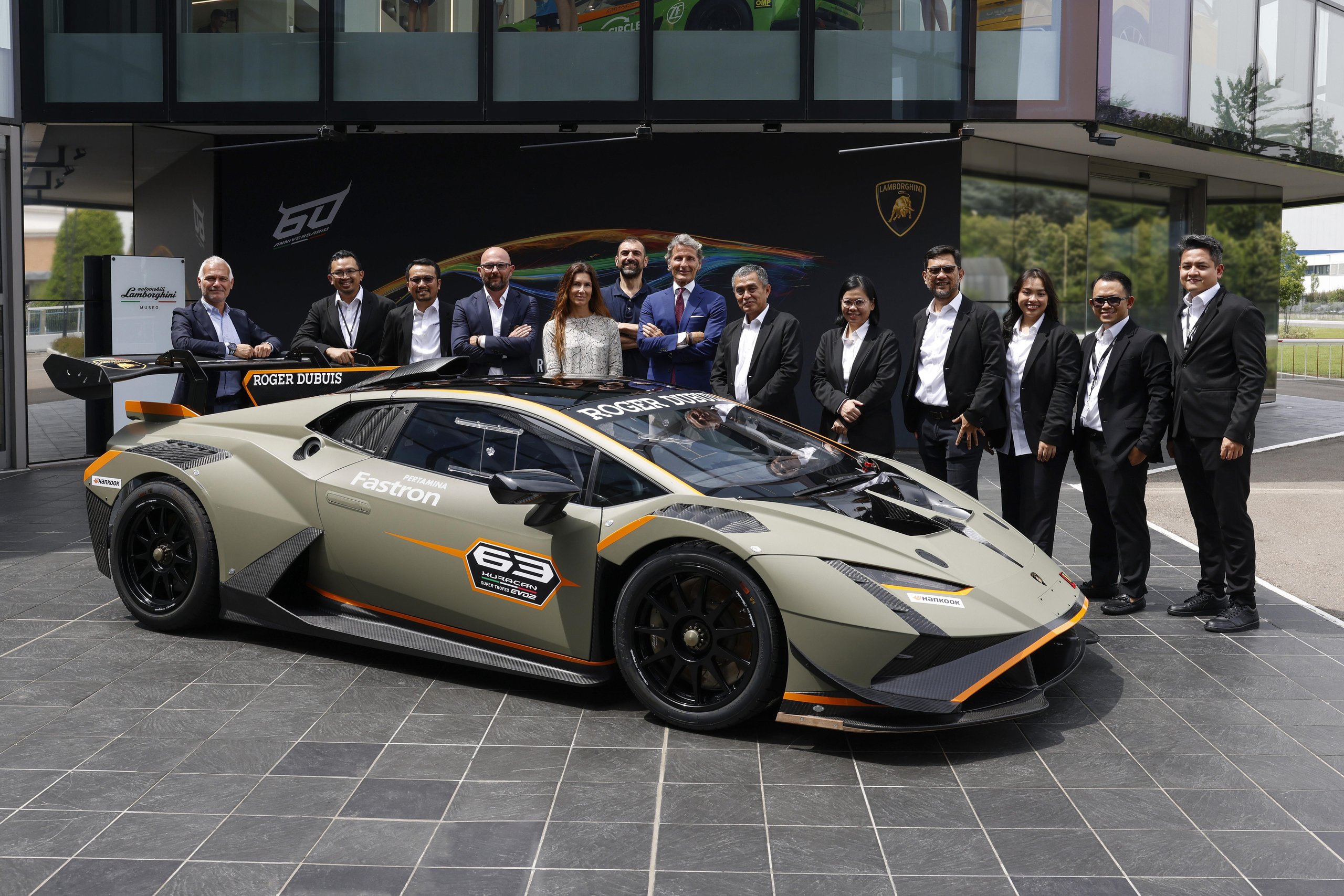 Lamborghini Renews Pertamina Lubricant Partnership Through 2025, Covering Super Trofeo, Gt3, And Sc63 Lmdh 7 Large group posing with lamborghini huracan super trofeo evo2 at outdoor event with 60th anniversary backdrop