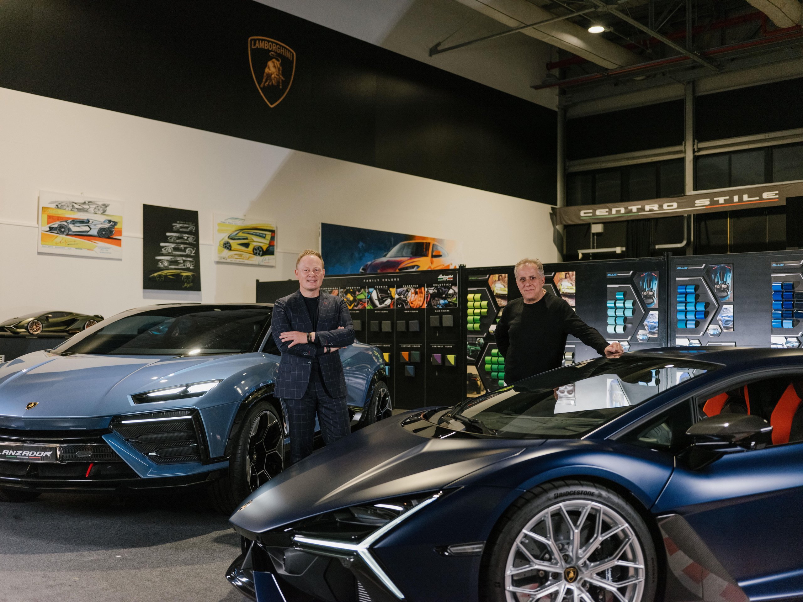 Lamborghini'S Design Chief Reveals How Depeche Mode And Vinyl Sleeves Shaped The Cars You Want To Buy 7 Mitja borkert and simon halfon standing between the blue lamborghini lanzador concept and dark blue revuelto with color swatches on the wall