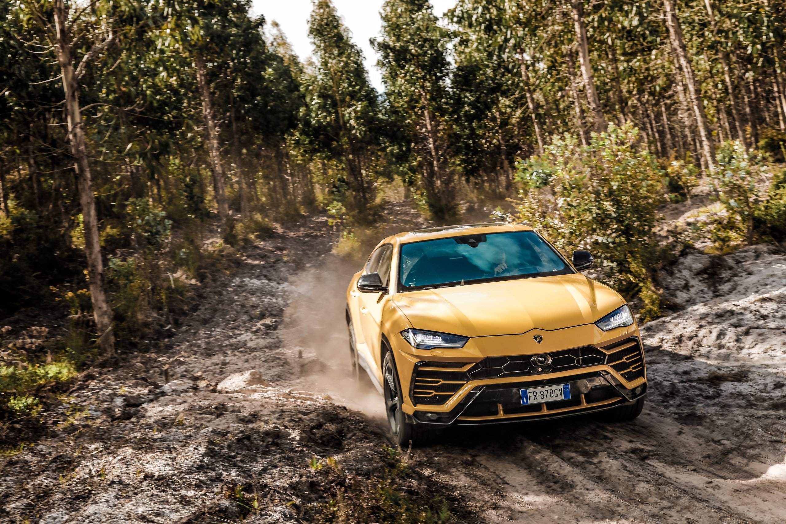 Lamborghini'S Q1 2022 Proves The Power Of Saying No: €178 Million In Profit By Selling Less Than The Market Wants 7 A yellow lamborghini urus kicking up dust on a dirt track through a forest