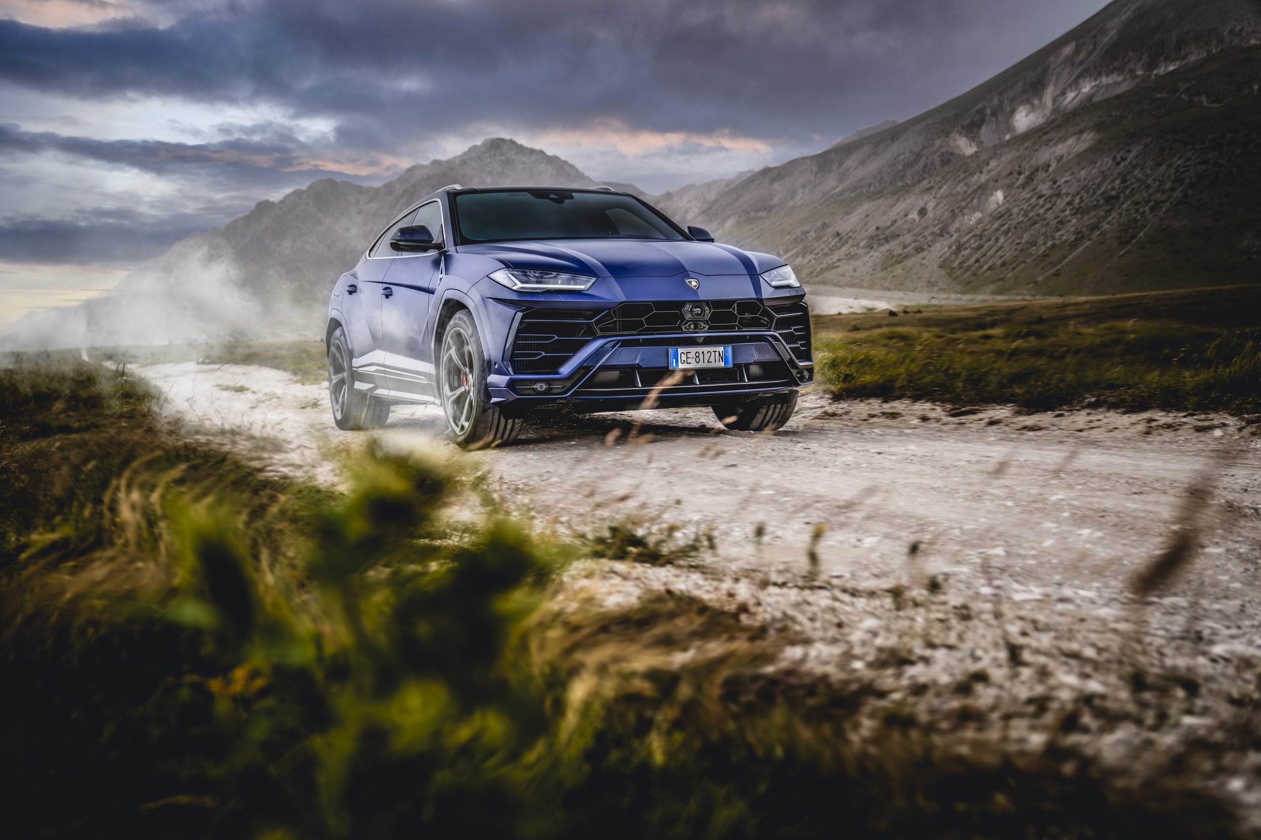 Lamborghini'S 12-Month Backlog Tells The Real Story Behind Its Best Quarter Ever 5 Blue lamborghini urus kicking up dust on a rugged dirt road with mountains in the background