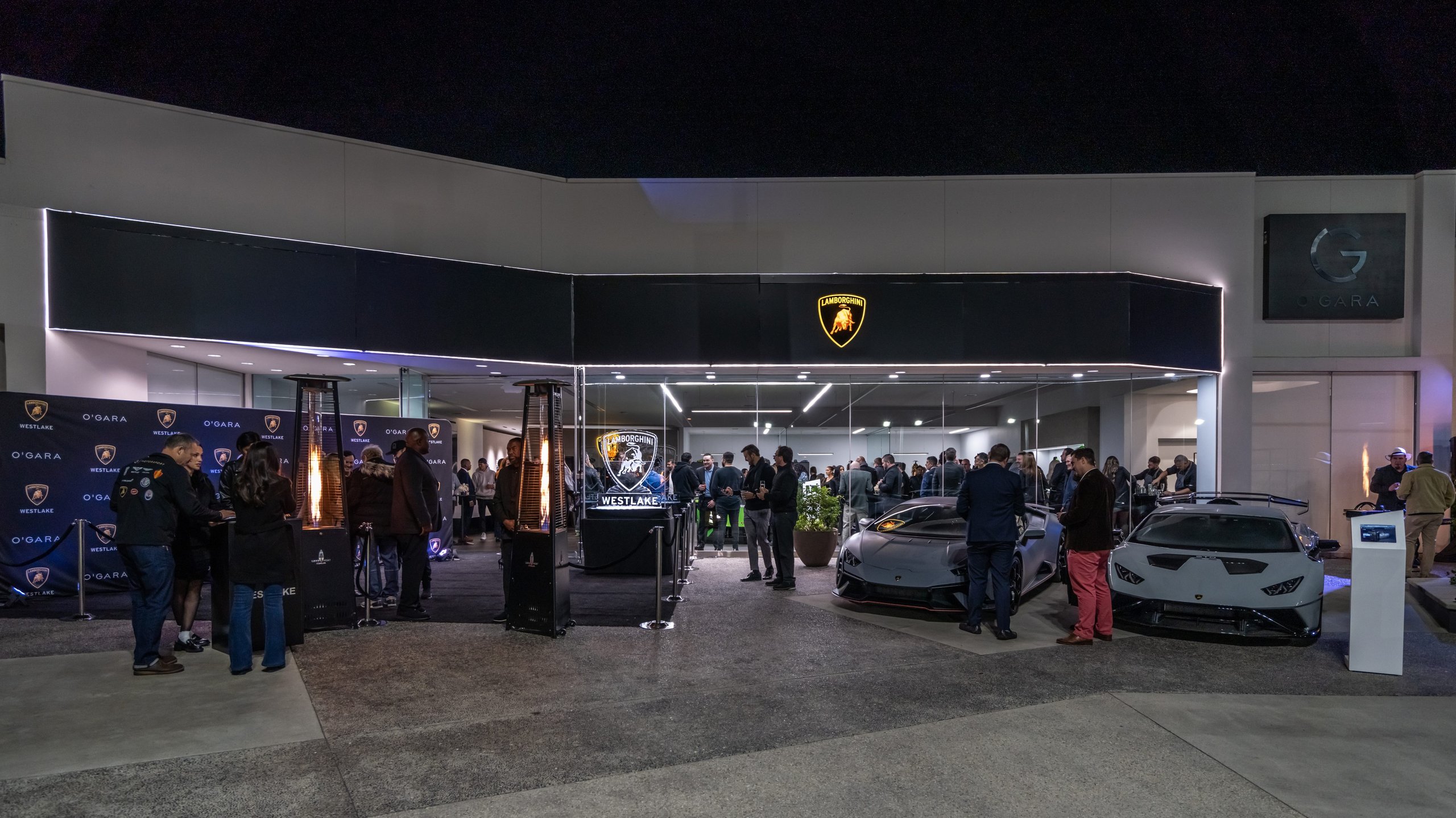 California And Florida Drive Lamborghini'S Record 2022 U.s. Sales As Two Showrooms Debut A New Retail Identity 9 Evening grand opening event outside a lamborghini dealership with guests gathered around a grey huracán tecnica and white huracán sto