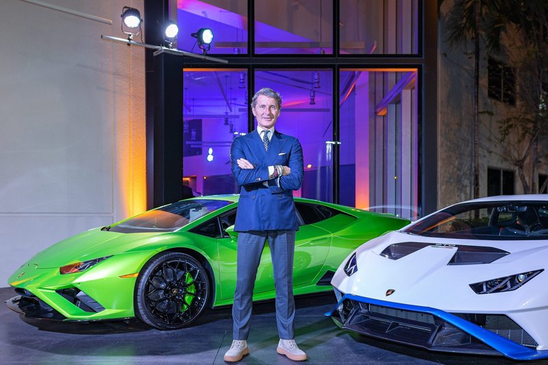 Stephan Winkelmann, CEO of Automobili Lamborghini, standing between a green Huracán Tecnica and a white Huracán STO at a U.S. showroom event