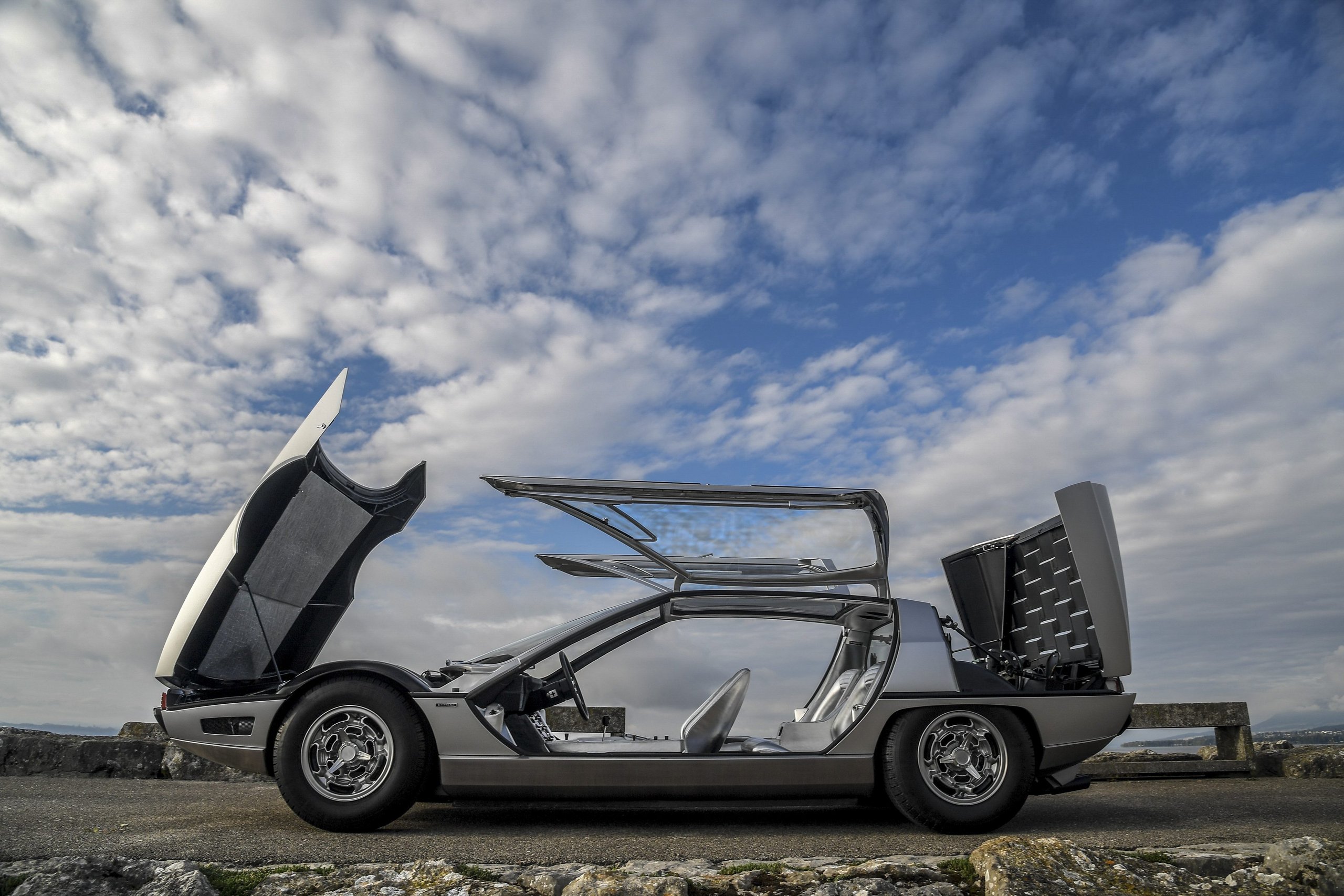 How Five Overlooked Firsts From The Marzal, Miura, Lm002, And Countach Built The Lamborghini You Know Today 3 Silver lamborghini marzal concept car with glass doors, hood, and engine cover open on a coastal road