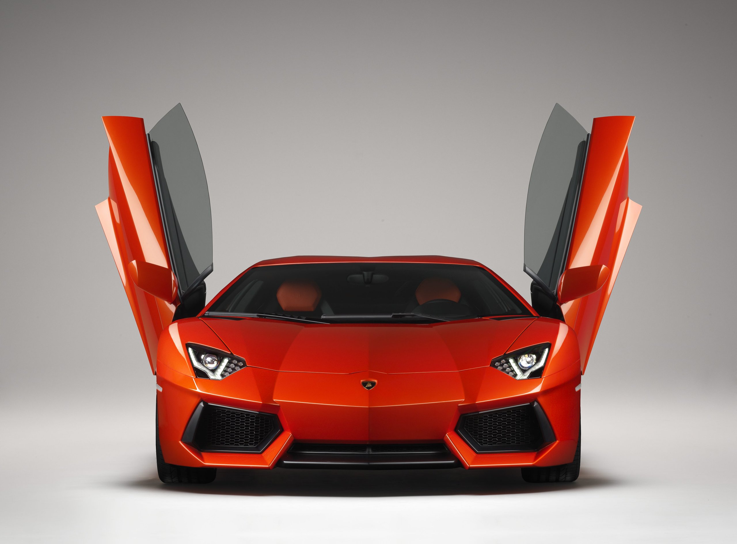How Five Overlooked Firsts From The Marzal, Miura, Lm002, And Countach Built The Lamborghini You Know Today 13 Orange lamborghini aventador lp 700-4 with both scissor doors open in a studio setting