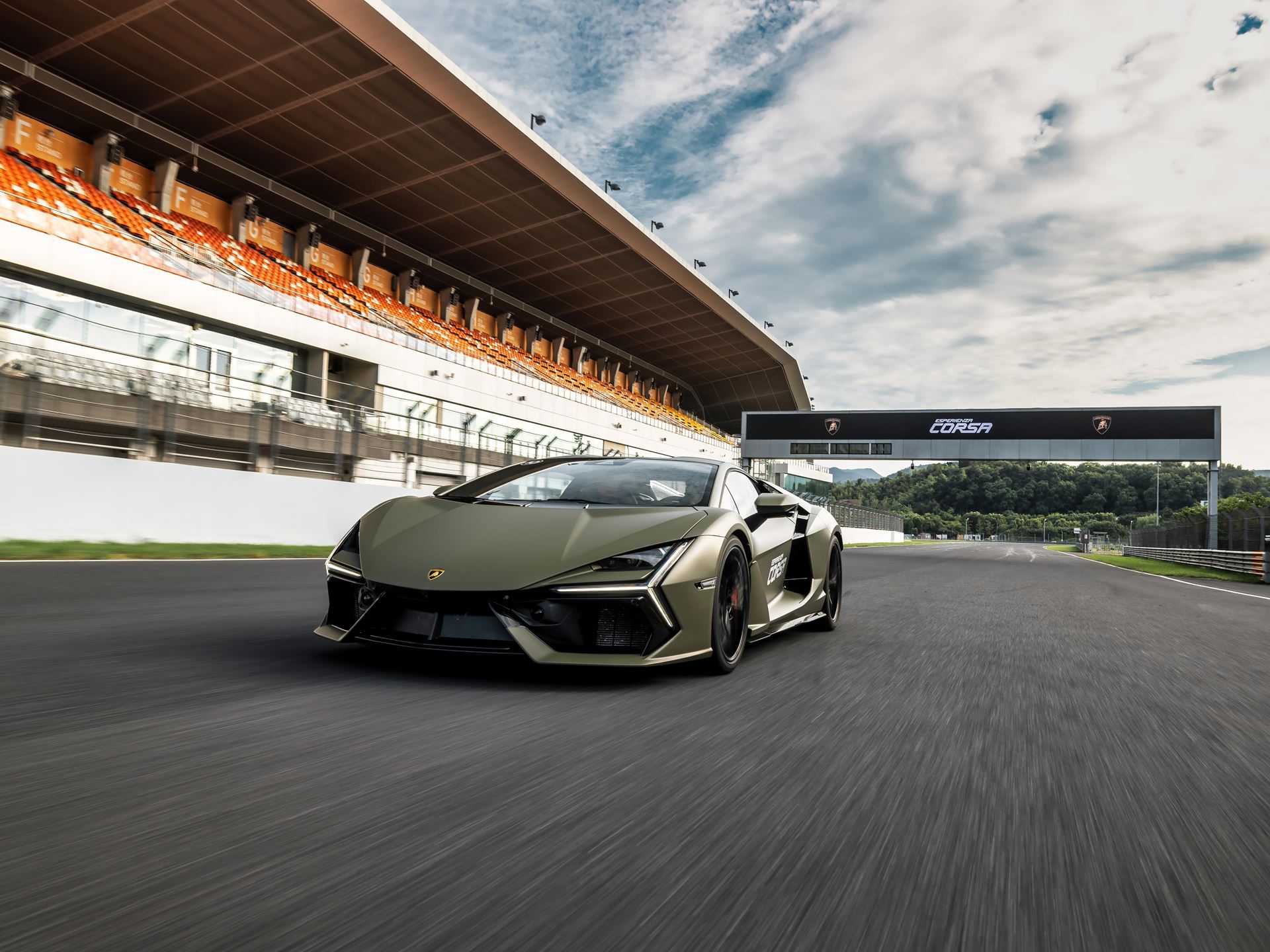 Lamborghini Brought The Revuelto To A Chinese Racetrack To Prove Its V12 Hybrid Belongs There 9 Olive green lamborghini revuelto speeding down the zhejiang circuit straightaway with esperienza corsa banner and grandstand visible