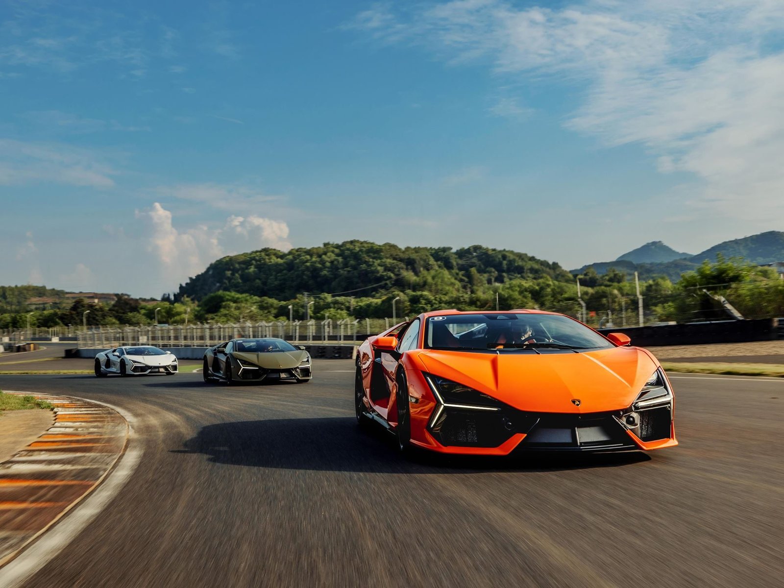 Orange Lamborghini Revuelto leading olive green and white Revueltos through a turn at Zhejiang International Circuit during Esperienza Corsa