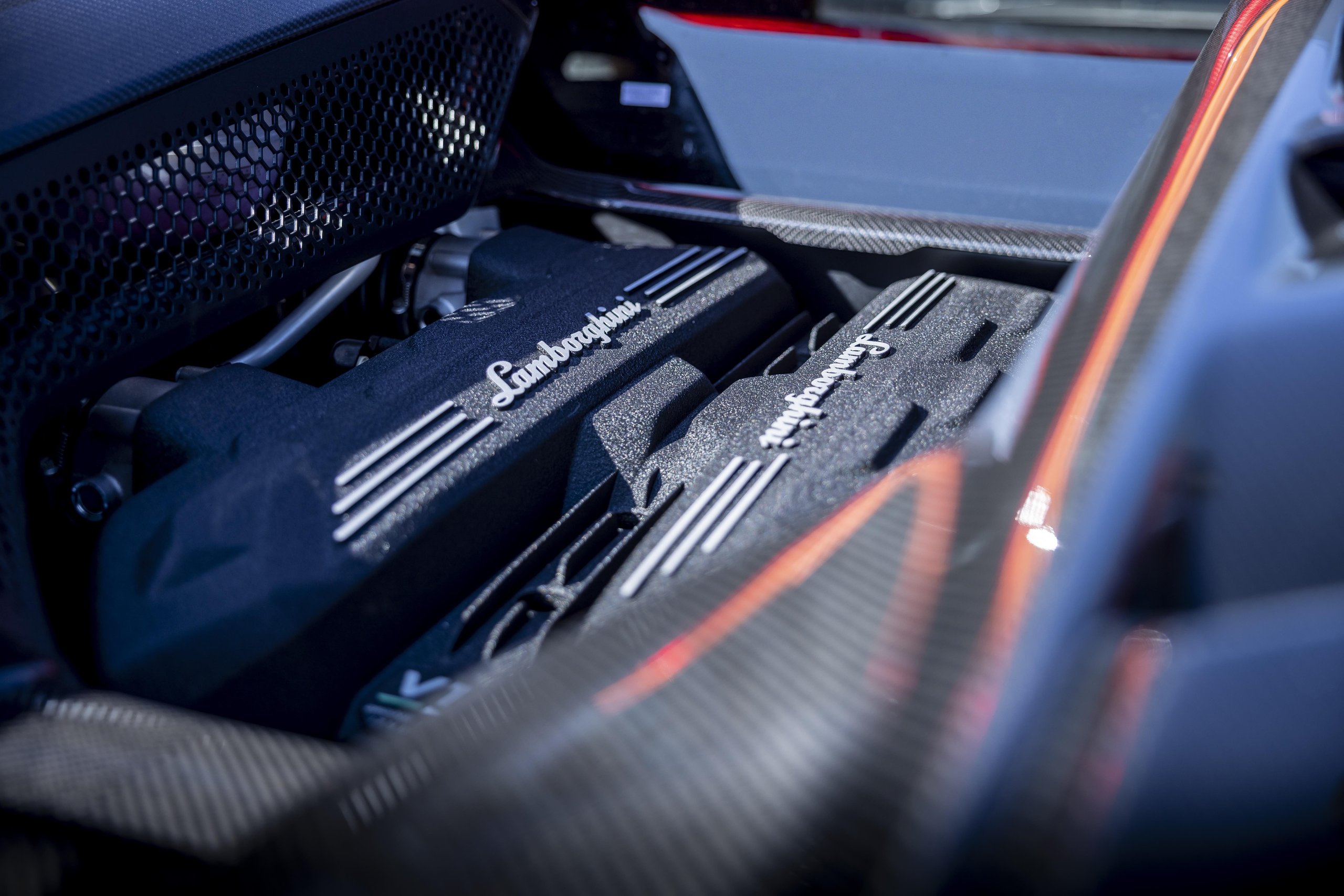 Lamborghini Sent The Revuelto Across Italy To Prove A 1,001 Hp Hybrid Can Still Be A Proper V12 Flagship 5 Close-up of the lamborghini revuelto v12 engine with lamborghini lettering and carbon fiber accents