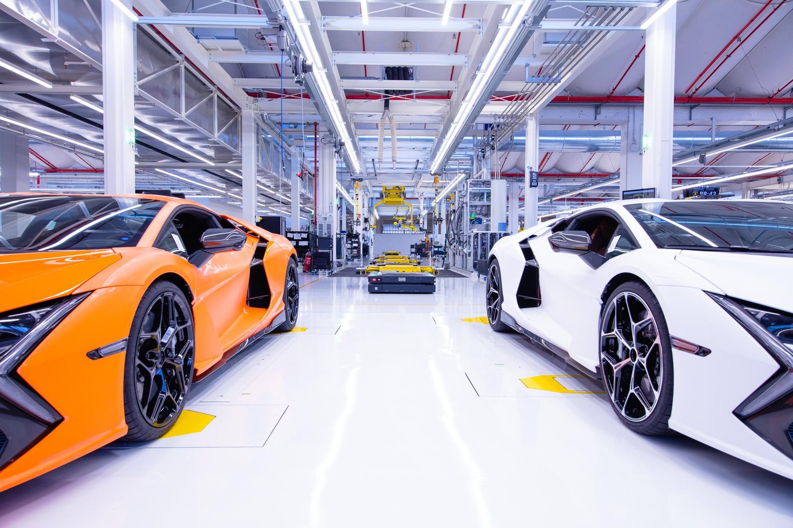 Orange and white Lamborghini Revuelto models on the factory floor at Sant'Agata Bolognese
