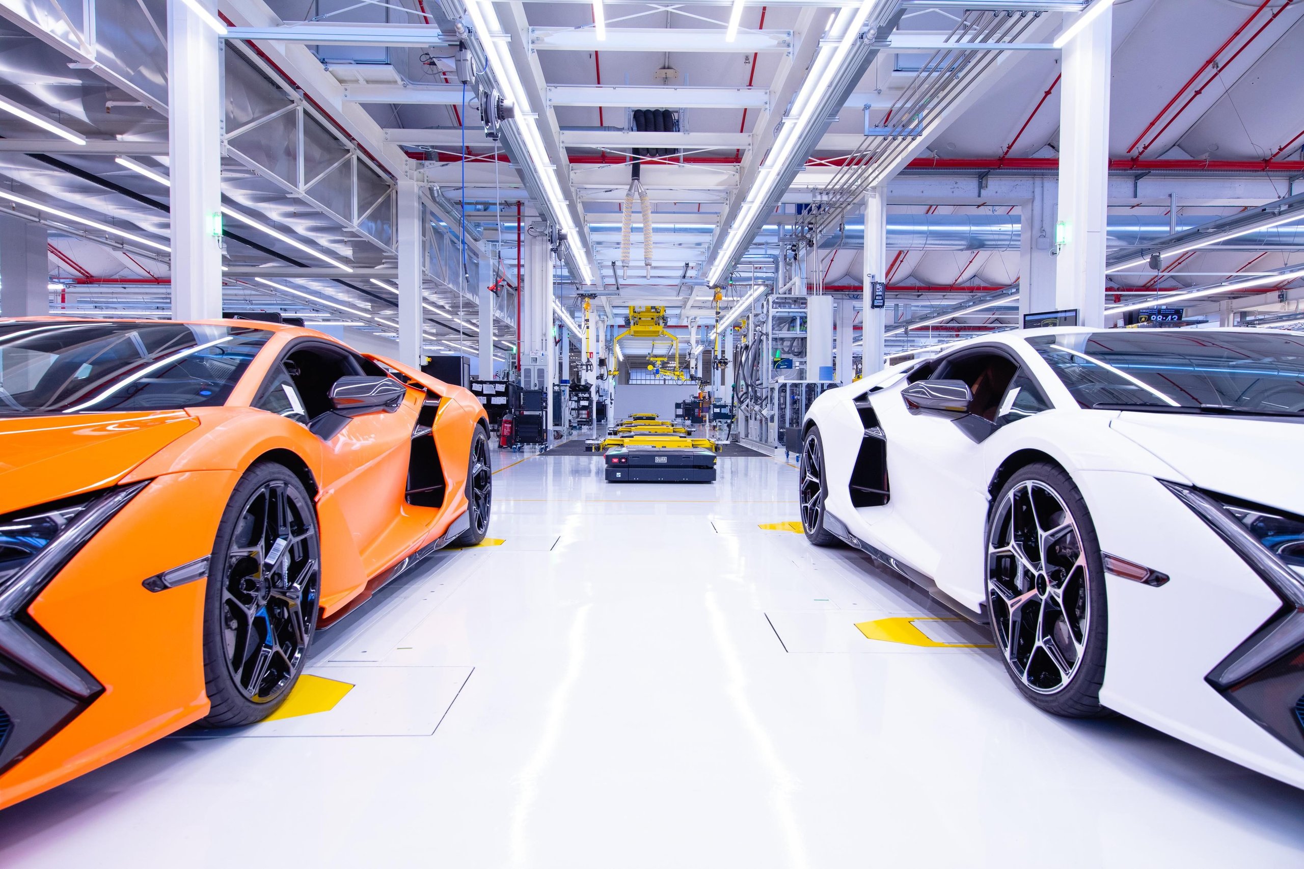 Orange and white lamborghini revuelto models on the factory floor at sant'agata bolognese