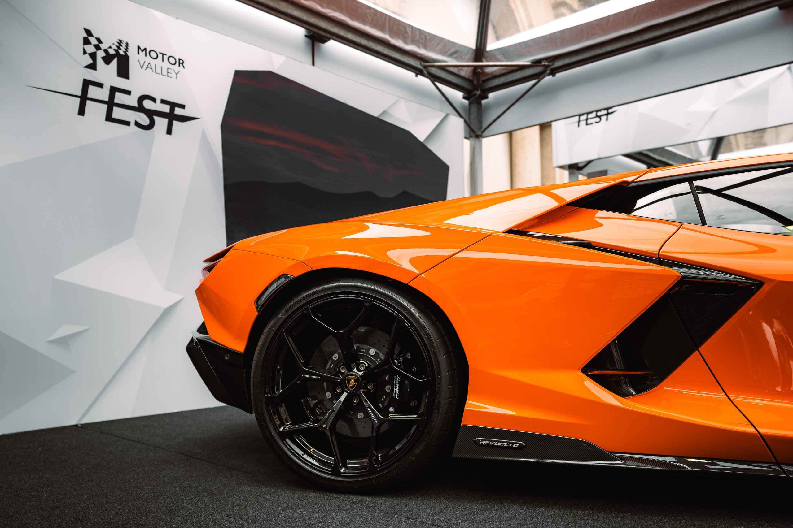 Motor Valley Fest 2023 Was Lamborghini'S First Public Statement That The Revuelto Era Had Arrived 5 Close-up of the rear-side profile of an orange lamborghini revuelto showing the rear wheel, brake caliper, and aerodynamic lines at motor valley fest 2023