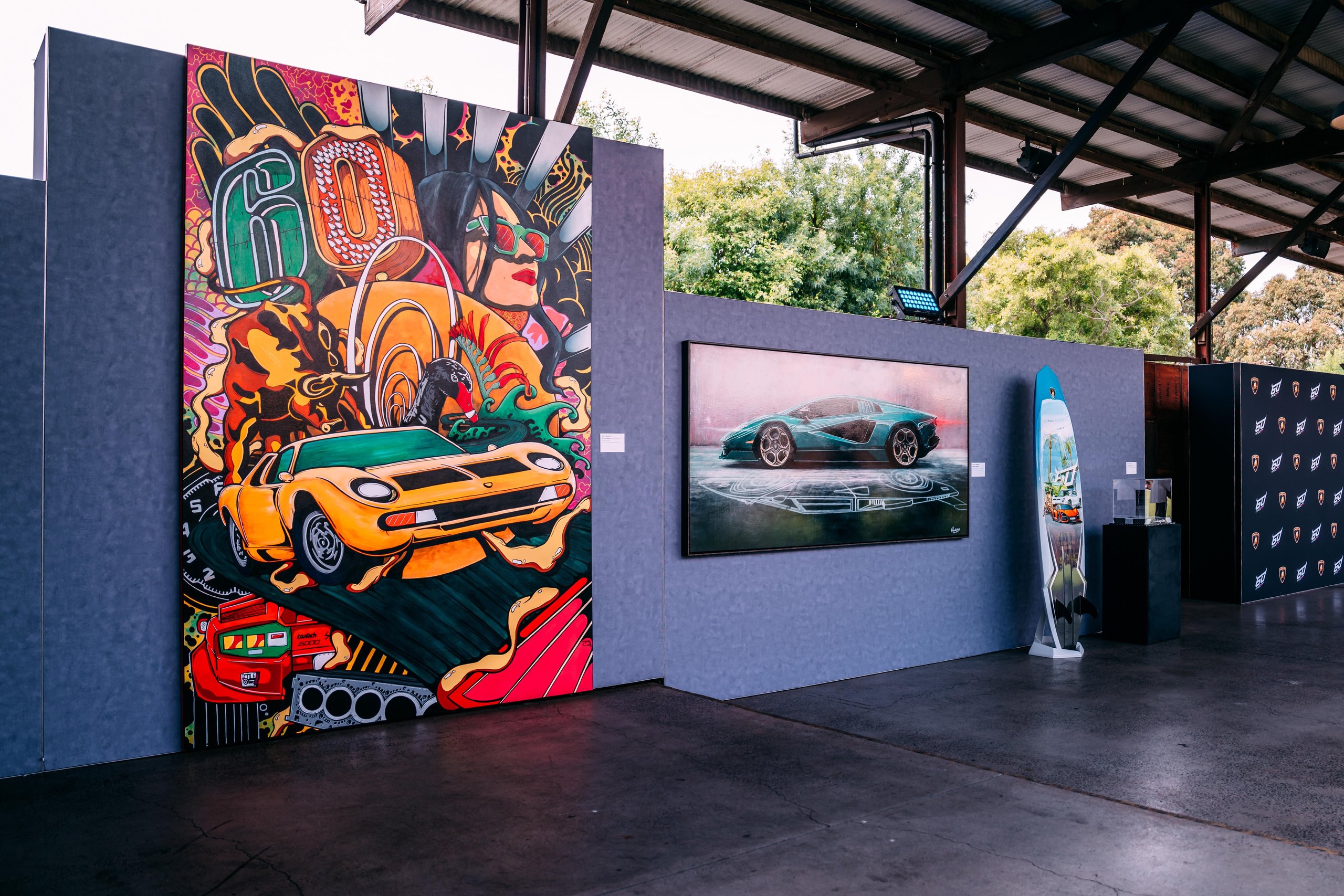 How Lamborghini Turned Melbourne Into A Rolling Museum For The Revuelto'S Oceania Debut 7 Art exhibition at the lamborghini oceania event showing a colorful miura mural, a revuelto painting, and a lamborghini-branded surfboard