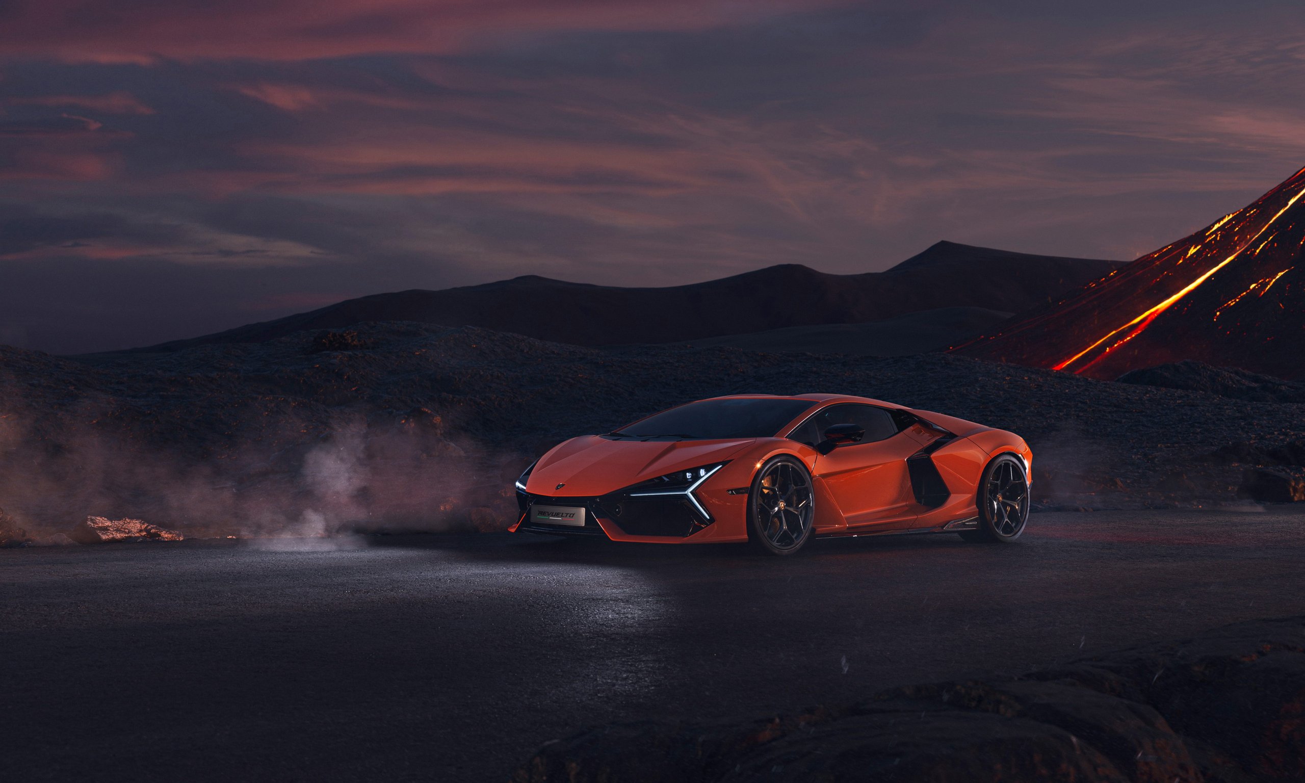 Lamborghini Revuelto: How Three Electric Motors Saved The V12 From Extinction 9 Orange lamborghini revuelto parked in a dramatic volcanic landscape at dusk with glowing lava in the background