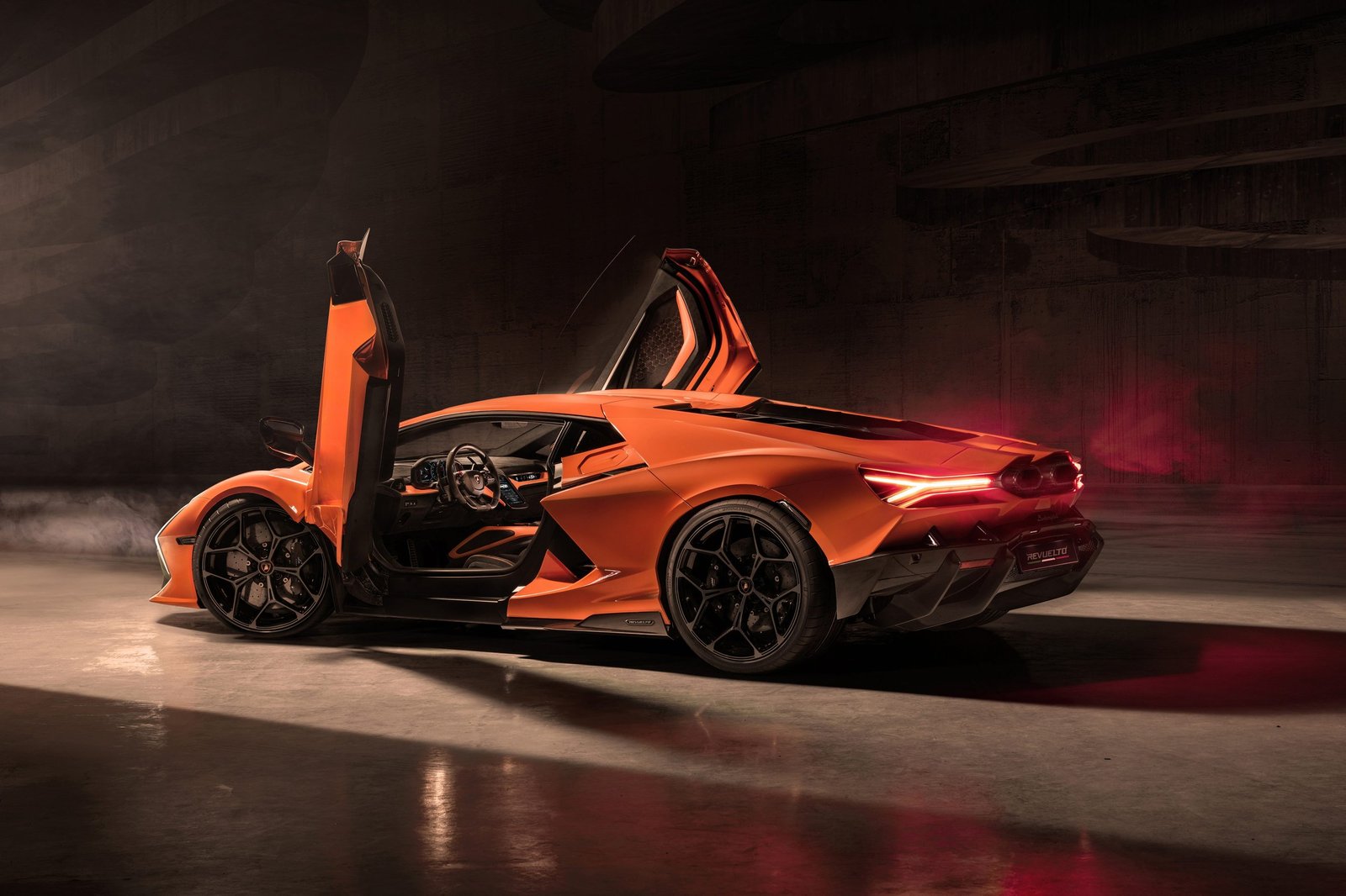 Orange Lamborghini Revuelto rear three-quarter view with both scissor doors open in a dark studio