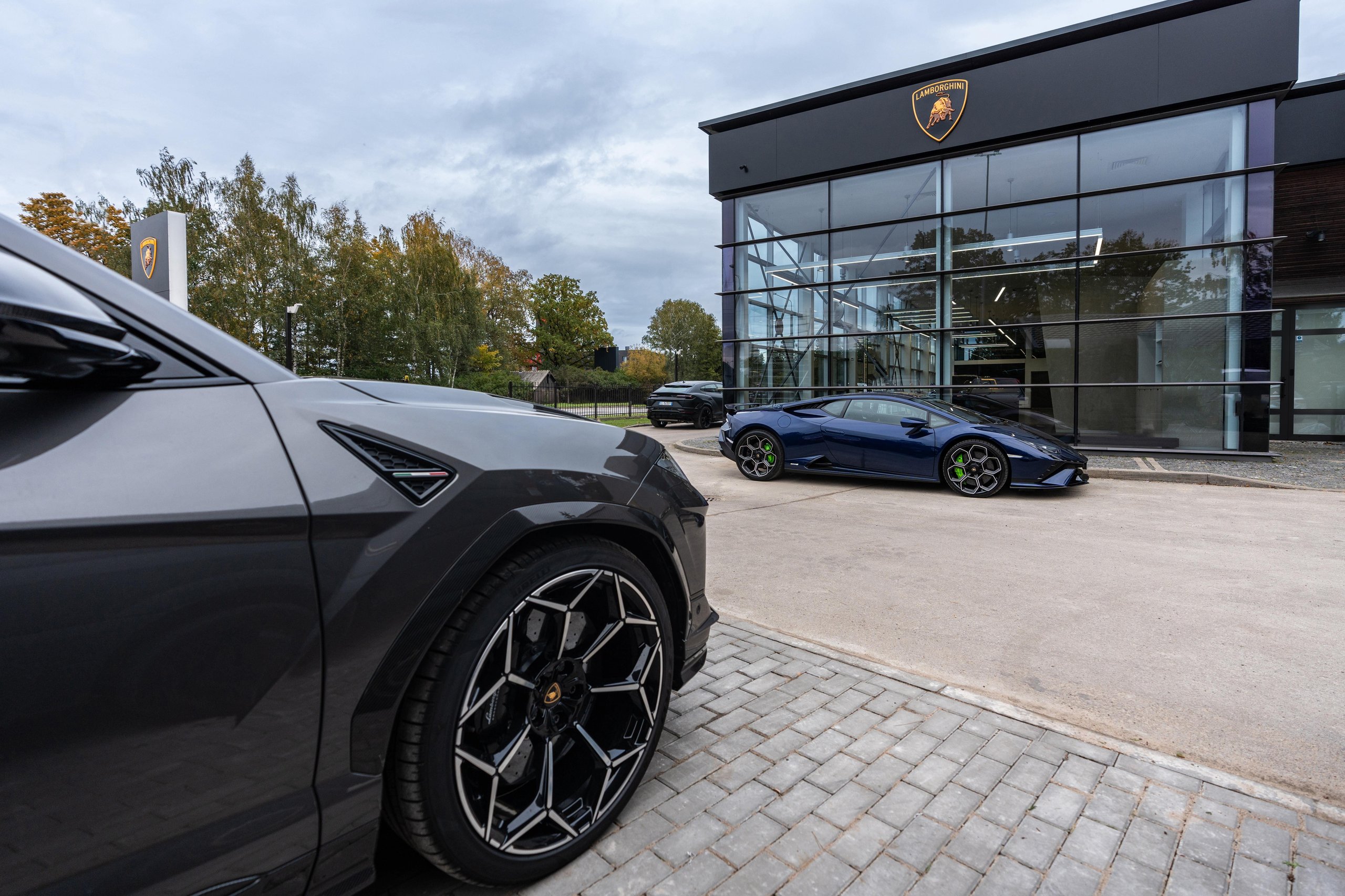 Lamborghini Riga: Why The Brand'S First Latvian Showroom Doubles As A Hybrid-Era Statement 11 A grey lamborghini urus and blue huracán tecnica parked in front of the lamborghini riga dealership