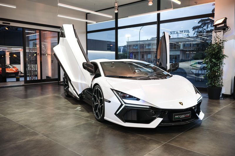 White Lamborghini Revuelto with scissor doors open displayed in the new Lamborghini Rome dealership showroom