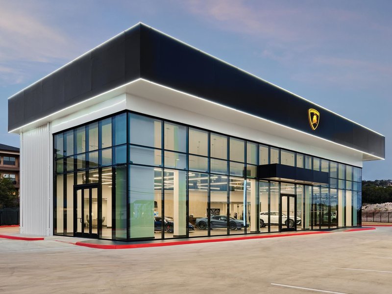 Lamborghini San Antonio dealership illuminated at dusk, showcasing vehicles through large glass windows