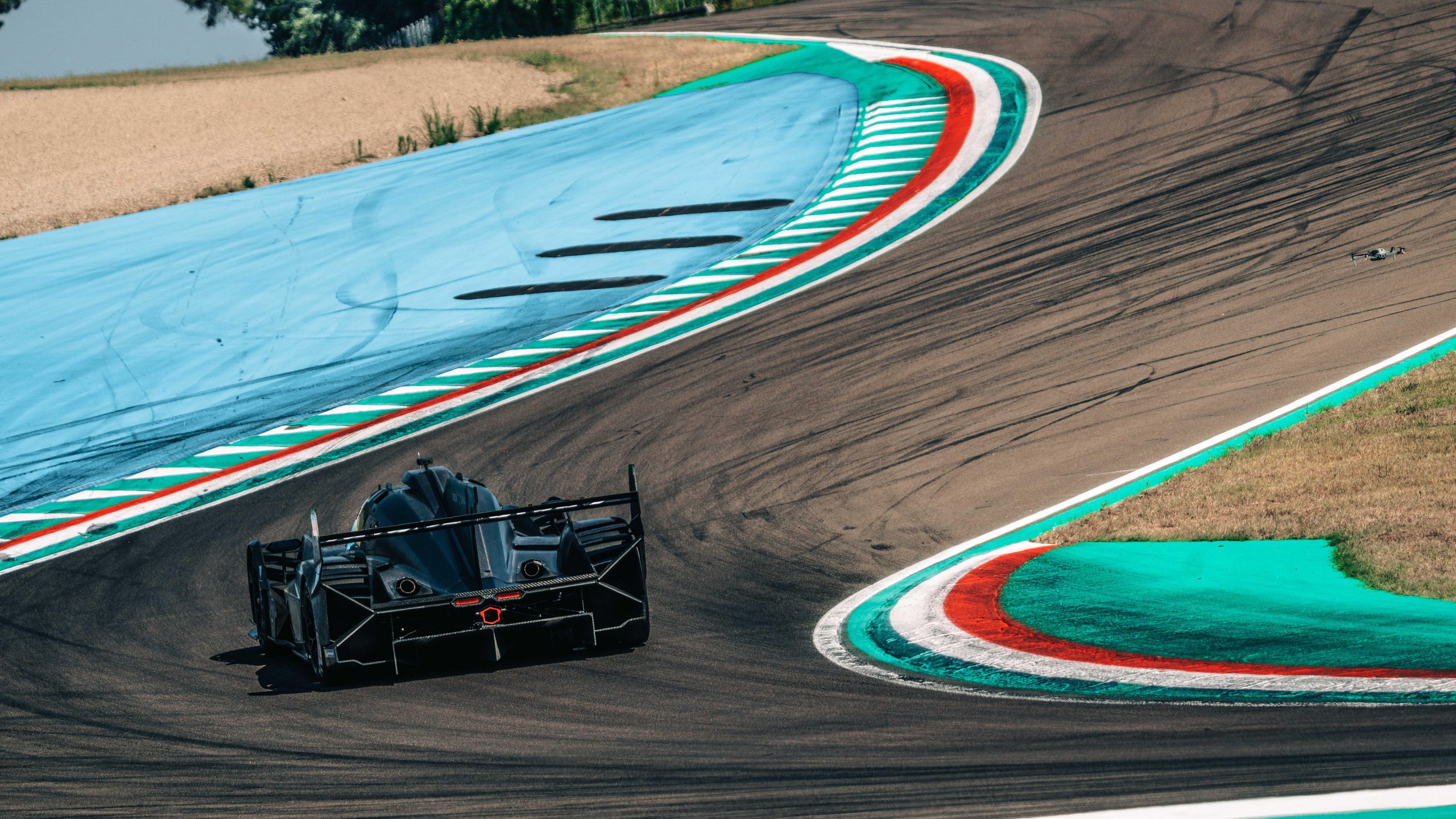 The Sc63'S First 1,500 Kilometers At Imola Promised A New Era. Then Reality Arrived. 5 Rear-three-quarter view of the lamborghini sc63 lmdh prototype exiting a turn at imola, showing the large rear diffuser and wing