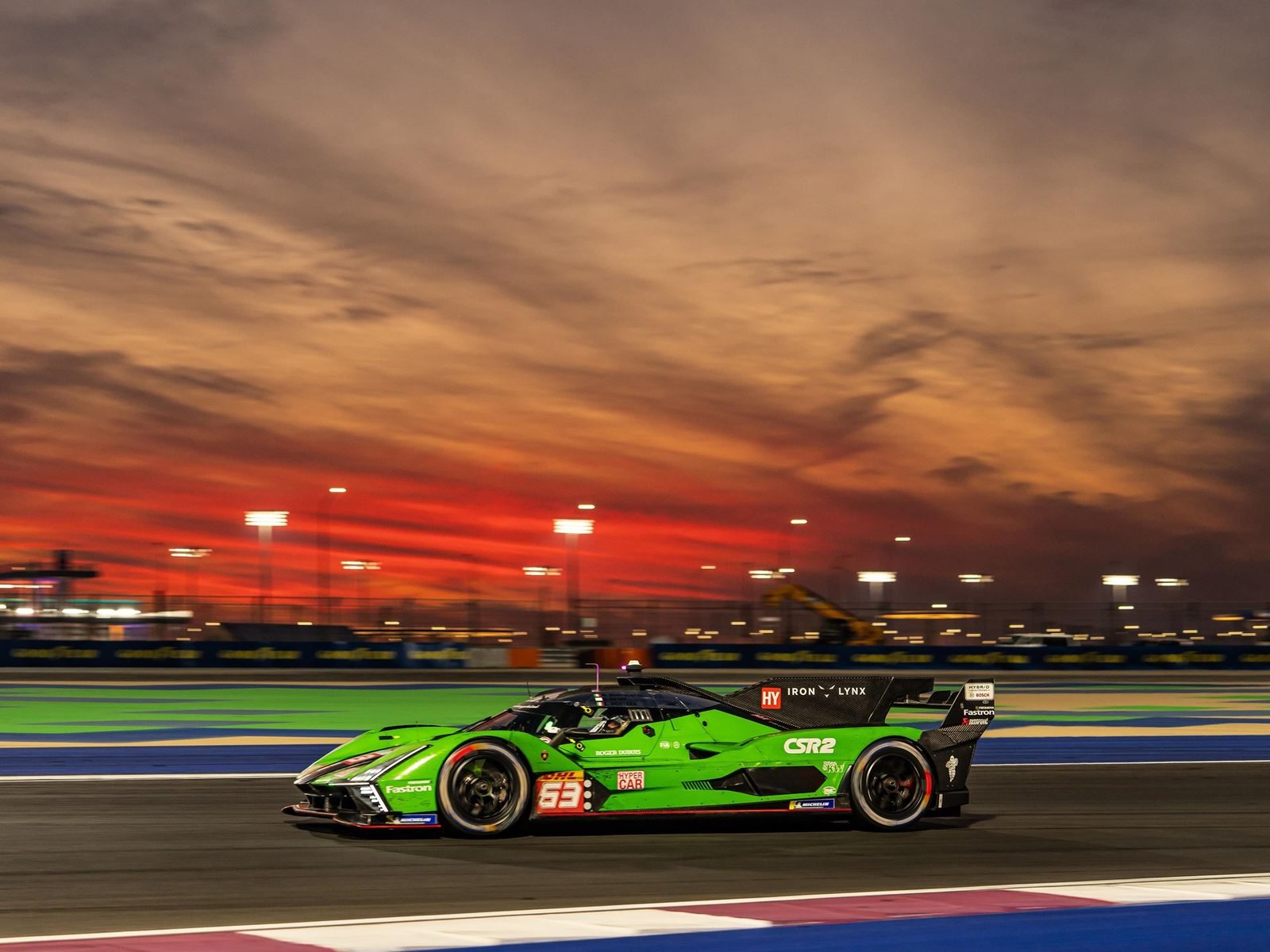 Lamborghini SC63 race car speeding on track at dusk with orange and purple sky