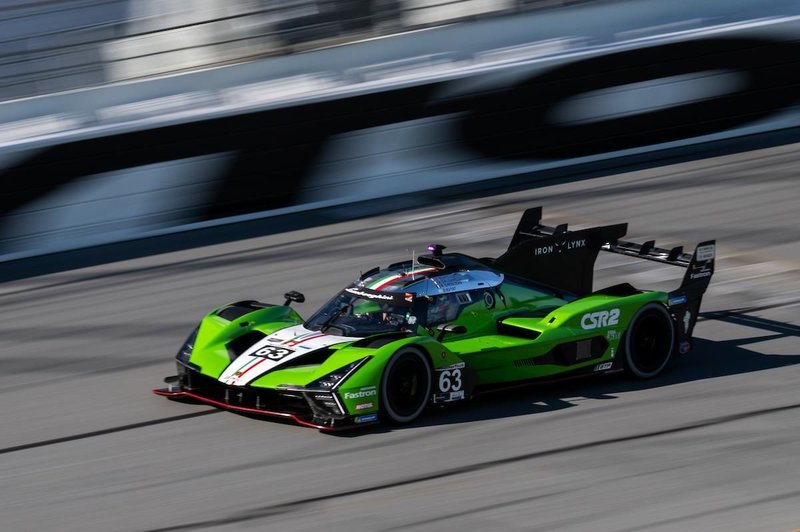 Lamborghini SC63 LMDh race car in green livery at speed on the Daytona track with motion blur