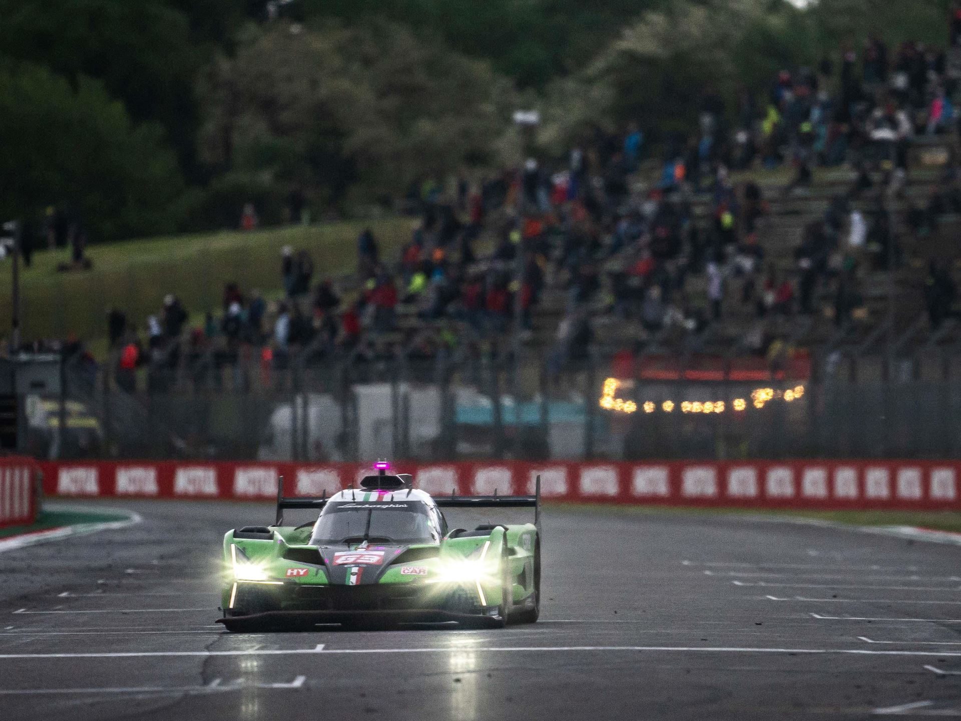 Lamborghini Sc63 Faces Its Final Exam At Spa Before Le Mans 7 Lamborghini sc63 approaching head-on with headlights illuminated on a damp racetrack, spectators visible in the background