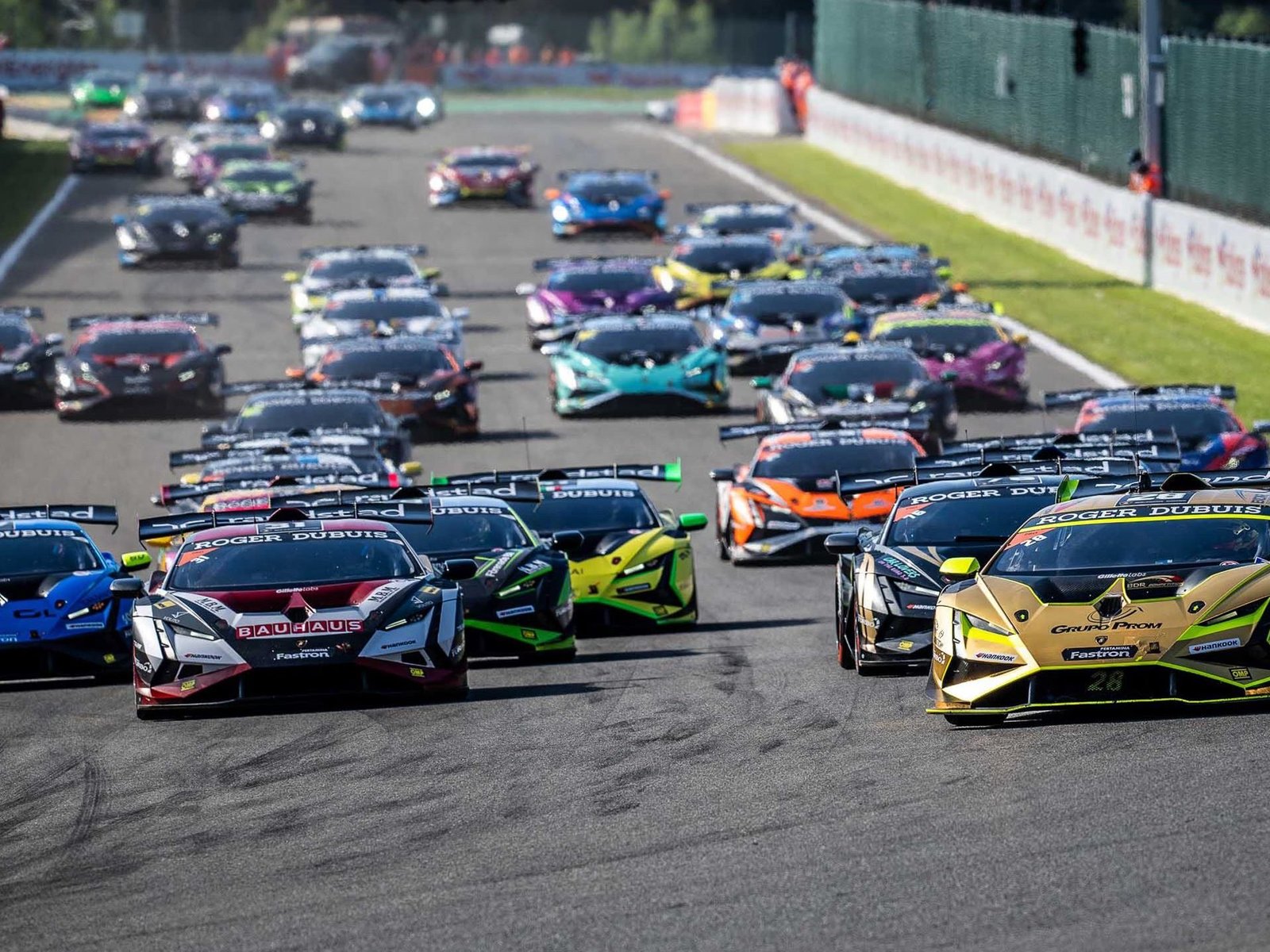 Large grid of Lamborghini Huracán Super Trofeo EVO2 race cars at the start of a race, showing various liveries and aggressive aerodynamic bodywork
