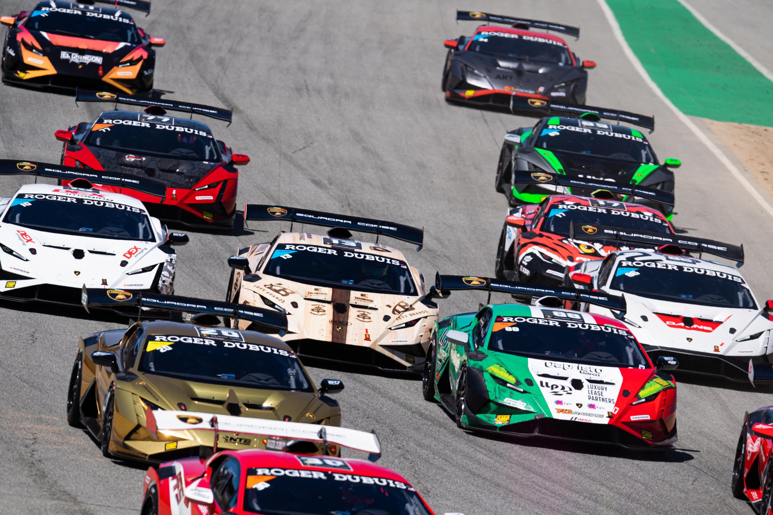 Lamborghini Super Trofeo'S 2024 Calendar Puts Customer Racing On The World'S Biggest Stages, Starting With Le Mans 3 Aerial view of multiple lamborghini huracán super trofeo evo2 race cars navigating a turn on a racetrack in various racing liveries
