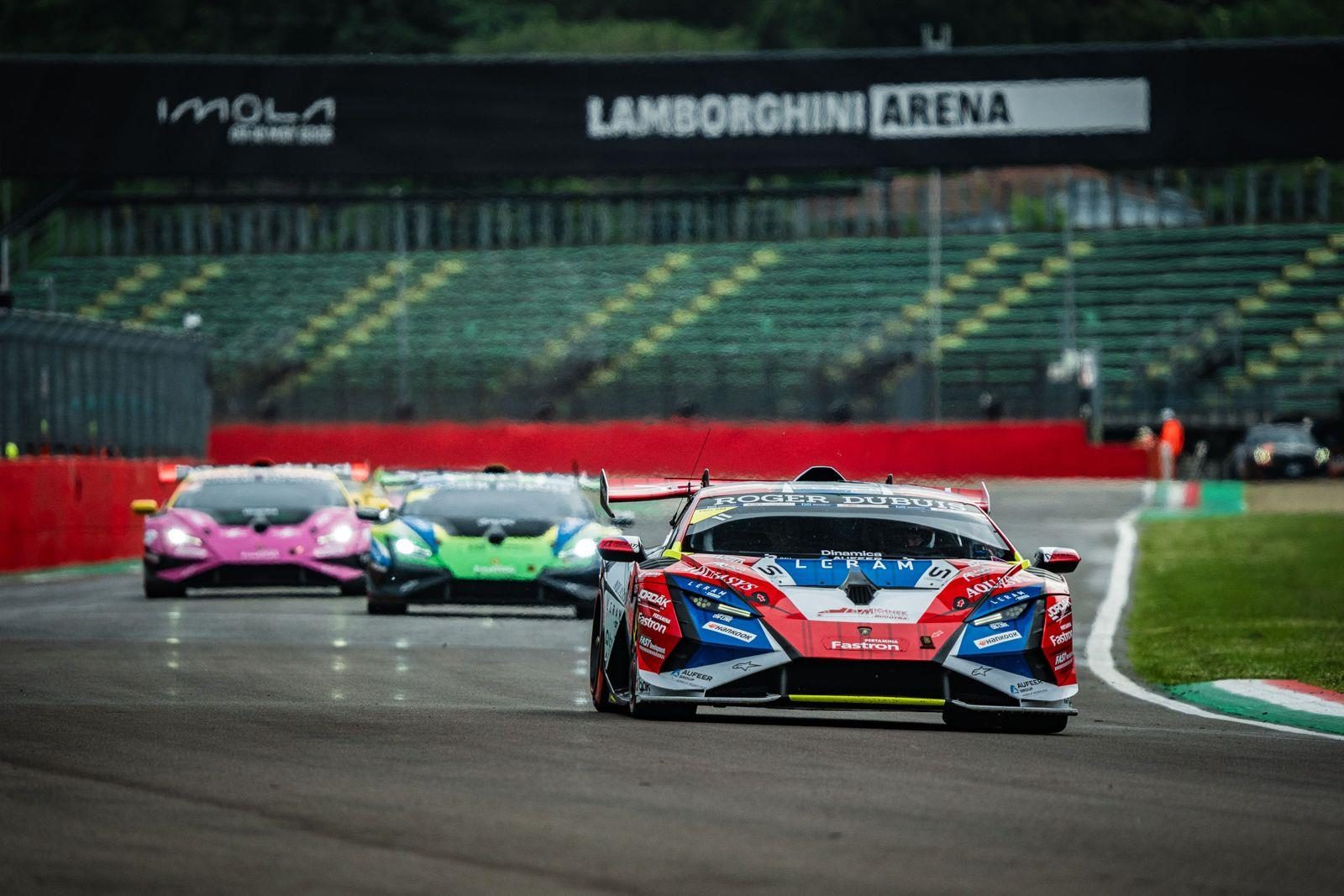 37 Cars, Four Titles Separated By Single Points: Lamborghini Super Trofeo Europe Hits Spa At The Boiling Point 3 Three lamborghini huracán super trofeo evo2 race cars in colorful liveries racing closely together toward the lamborghini arena banner