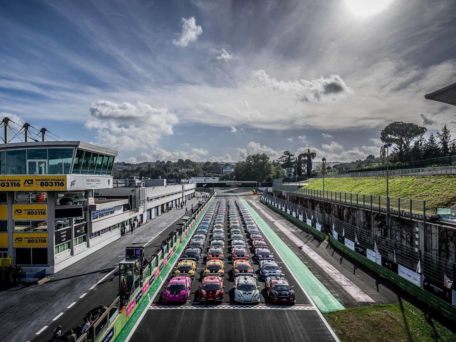 Lamborghini Huracán Super Trofeo EVO2 race cars lined up on the starting grid at Autodromo Vallelunga with grandstands and green hills in the background