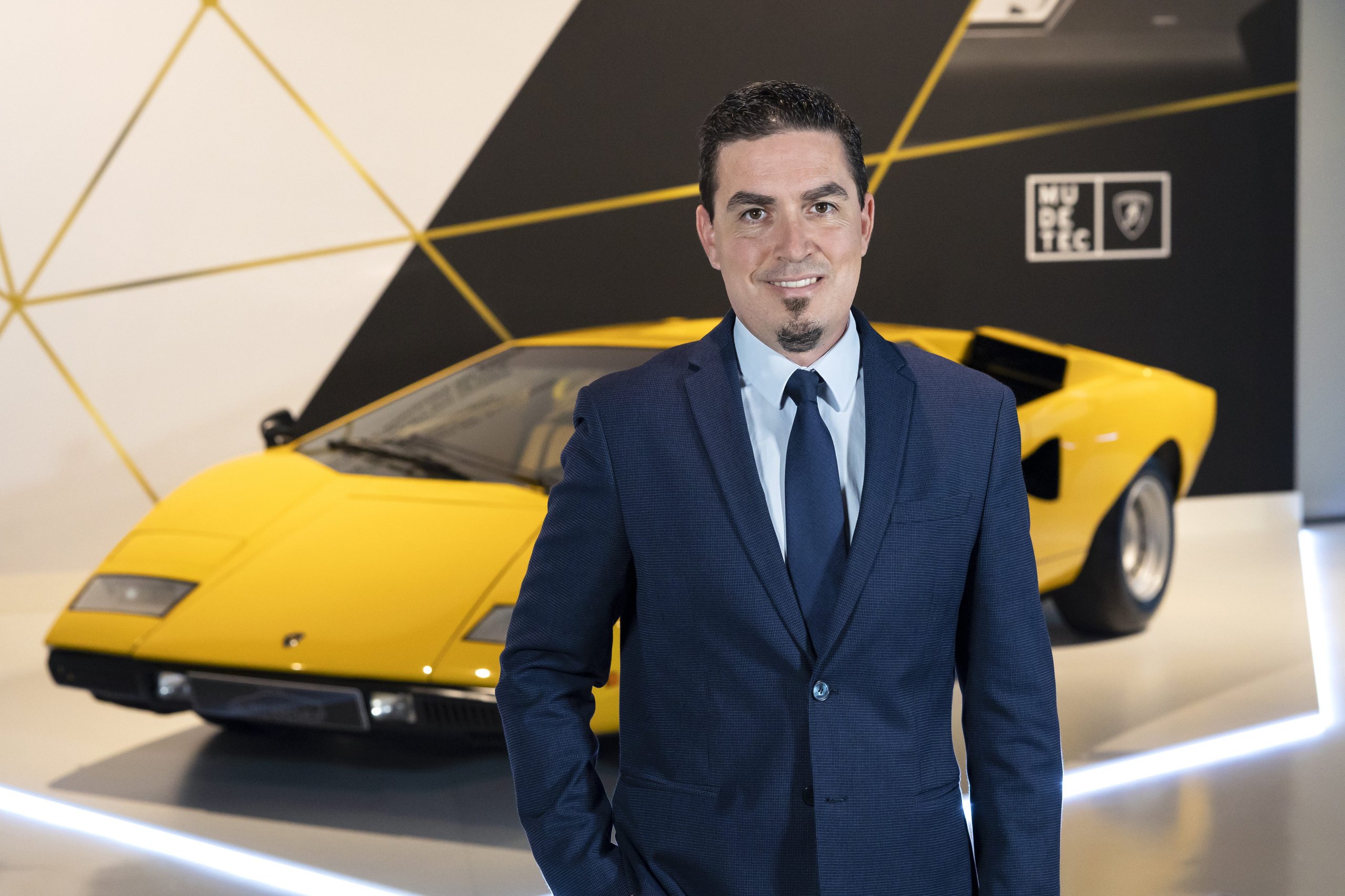 How Lamborghini'S Chief Procurement Officer Kept The Factory Running Through Pandemic, Chip Shortage, And War 3 Silvano michieli in a dark suit standing confidently in front of a classic yellow lamborghini countach lp400