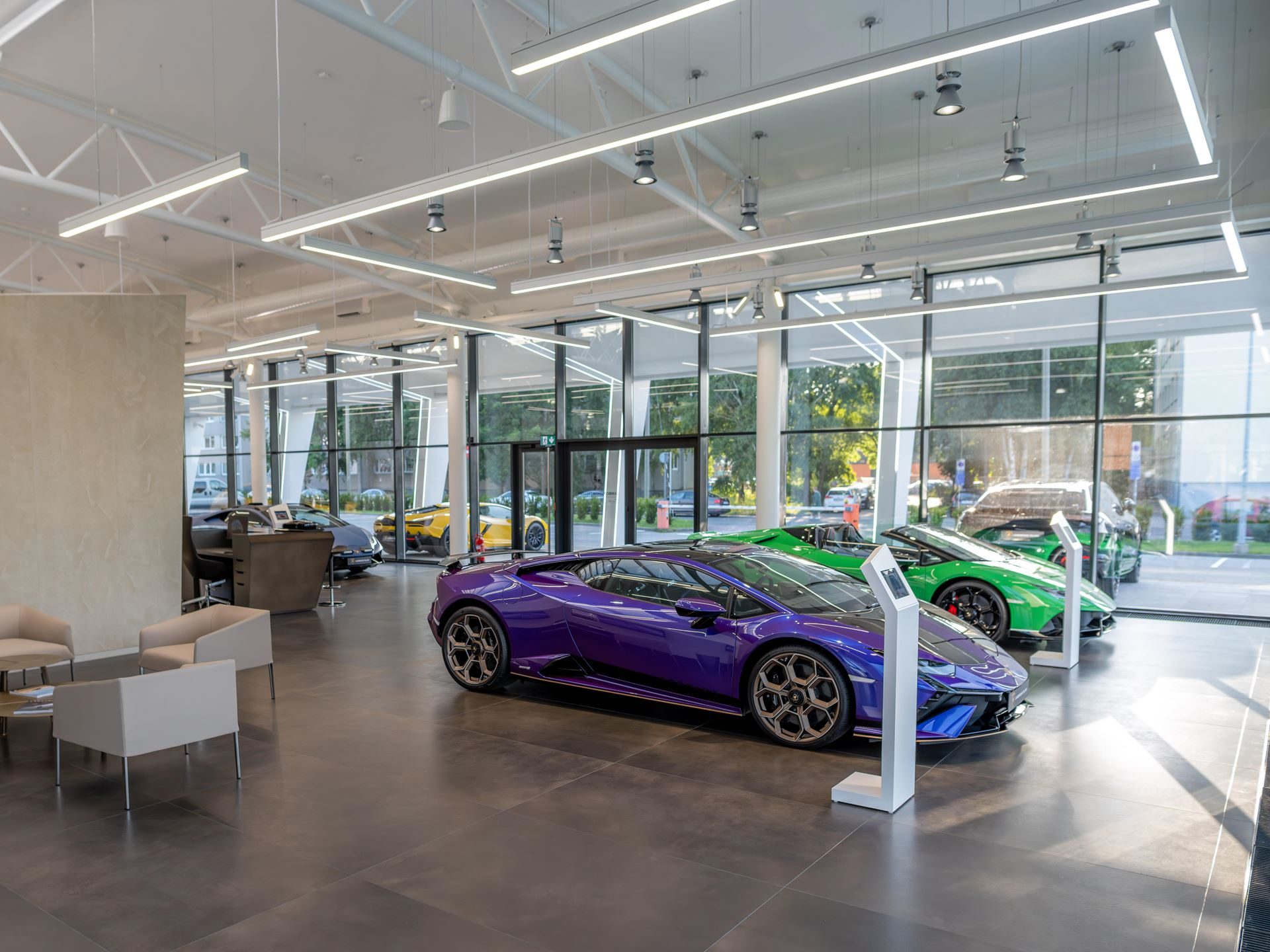 Lamborghini Tallinn'S New Showroom Pairs A Choir, A Diablo, And The Urus Se To Sell Its Hybrid Future 9 Interior of the lamborghini tallinn showroom featuring a purple huracan, green huracan, and yellow revuelto on display