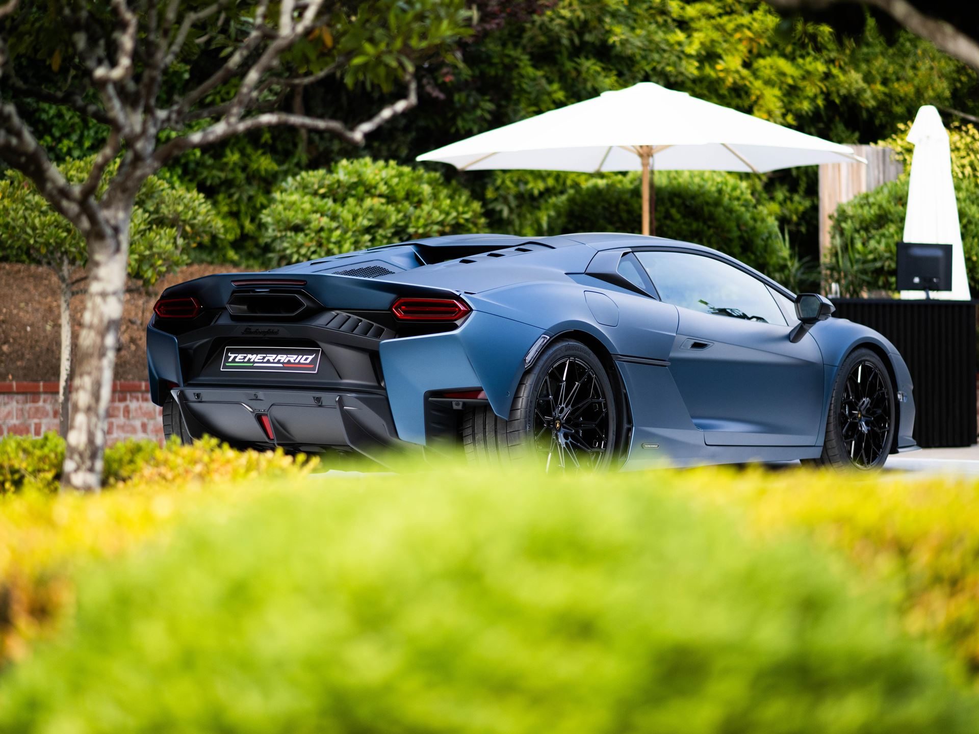 Lamborghini Staged Its Hybrid Future Around The Temerario At Monterey Car Week 5 Rear three-quarter view of the matte blue lamborghini temerario showing temerario badging and y-shaped taillights