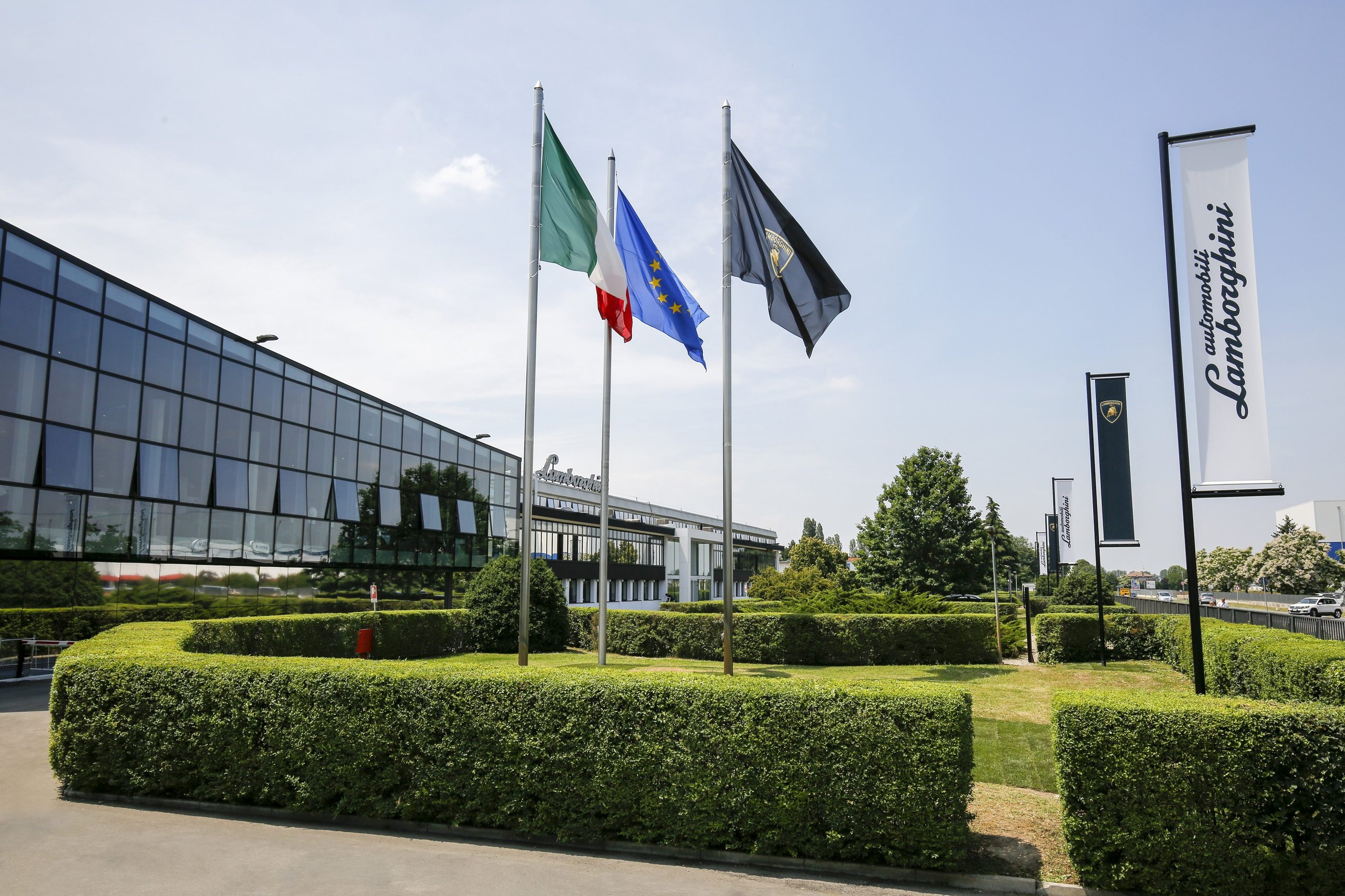 Italy'S Most Desirable Automotive Employer Builds Lamborghinis, And That Matters More Than You Think 3 Exterior of automobili lamborghini headquarters with italian, eu, and lamborghini flags