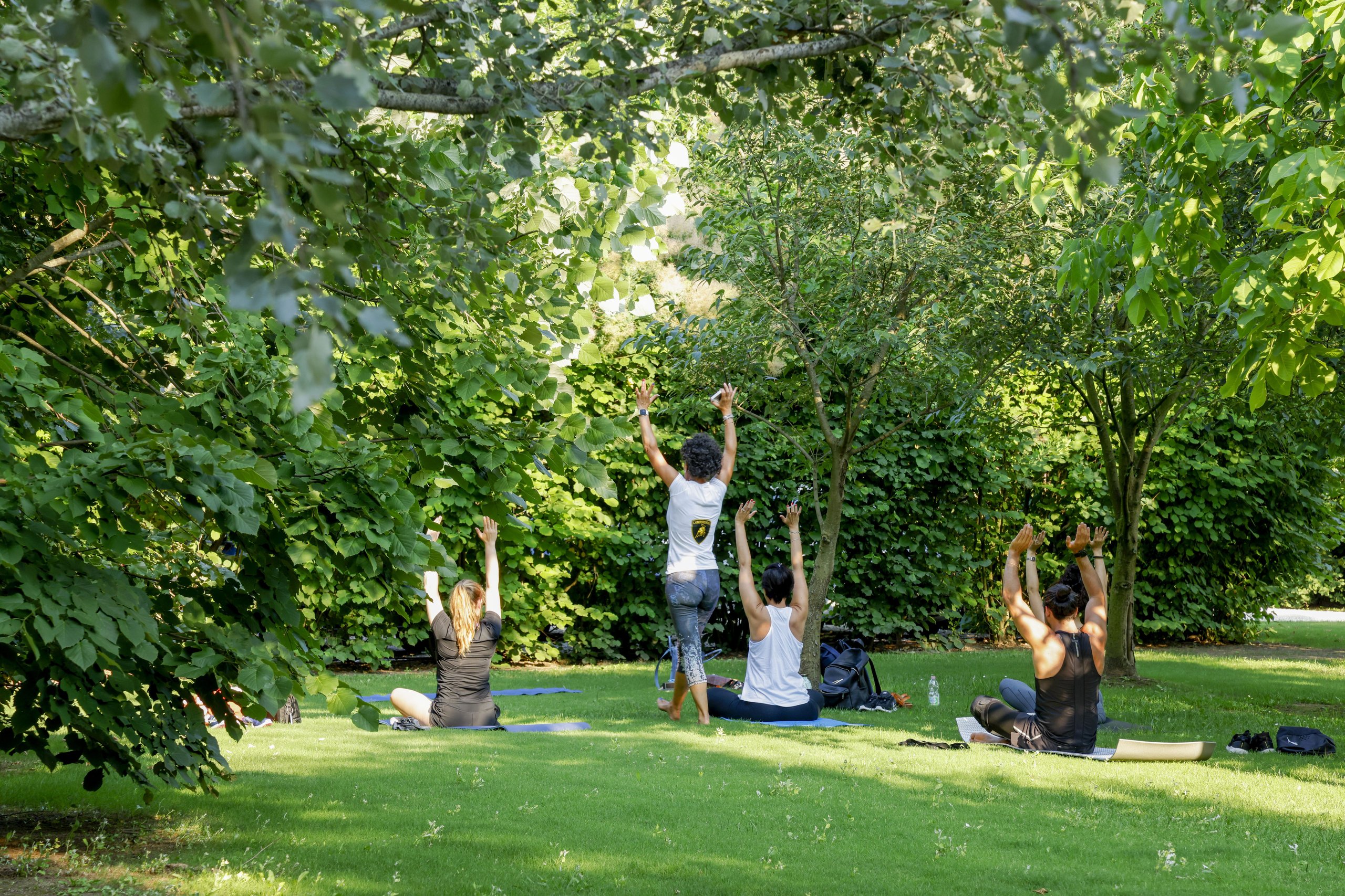 Italy'S Most Desirable Automotive Employer Builds Lamborghinis, And That Matters More Than You Think 5 Four people practicing yoga outdoors in a green park setting as part of employee wellness activities