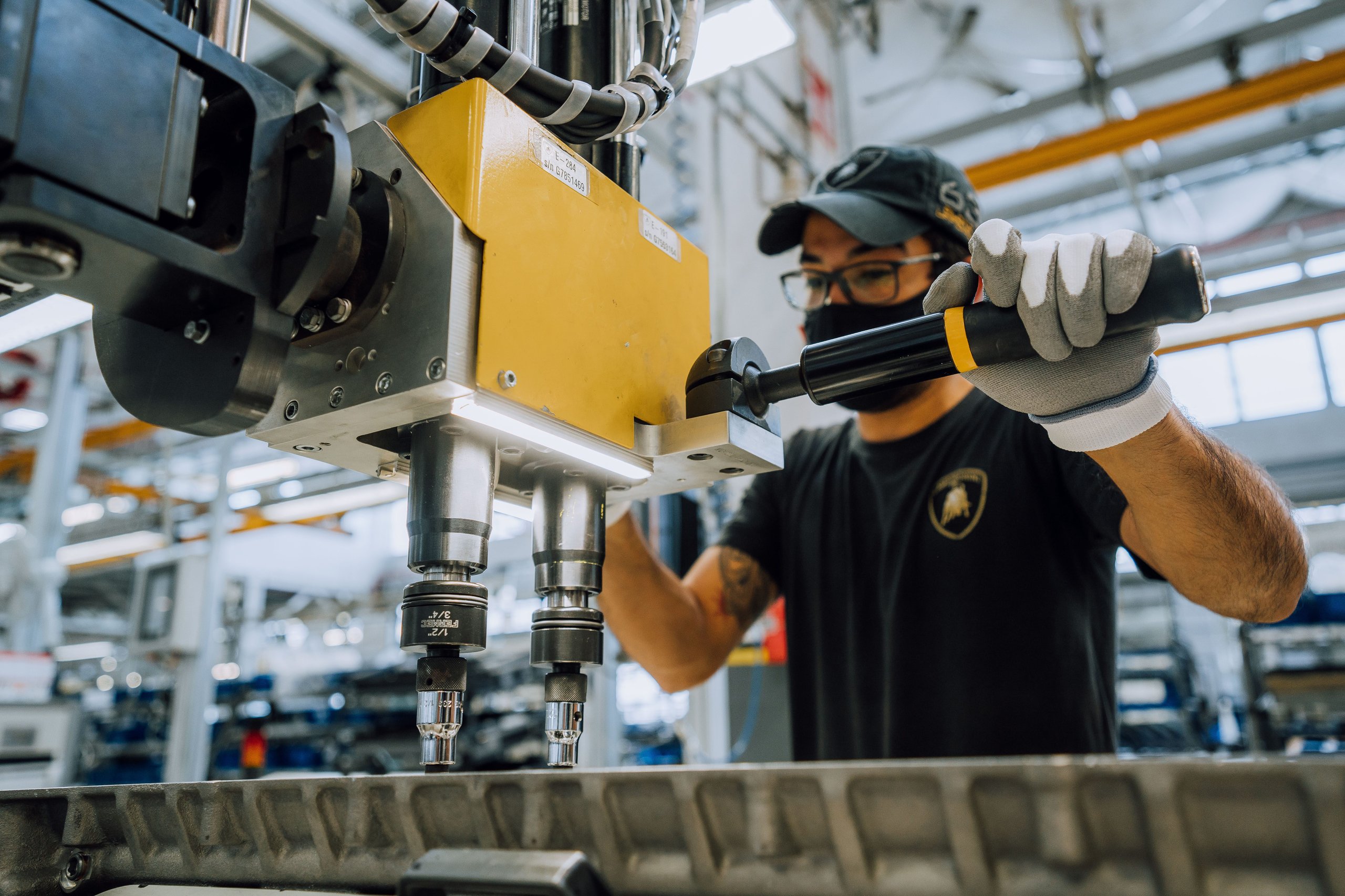 Close-up of a lamborghini employee using specialized tooling on a component during precision assembly at the factory