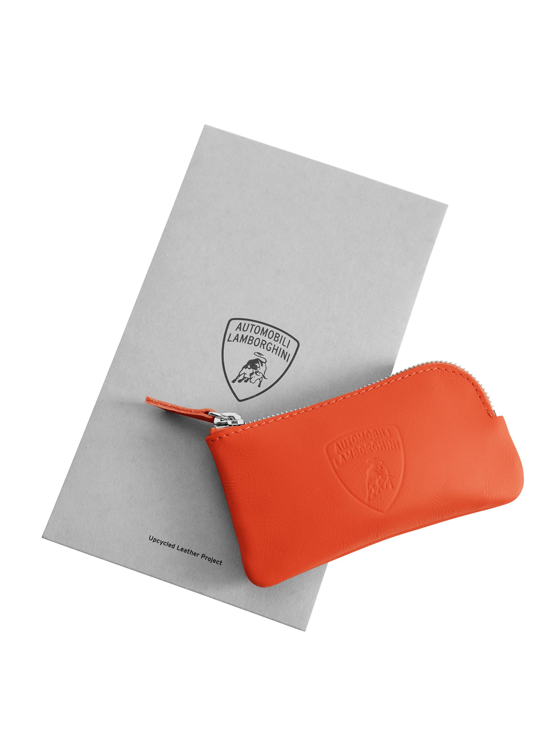 Lamborghini'S Upcycled Leather Project Turns Supercar Factory Scraps Into Covetable Accessories 3 Orange leather zippered pouch with embossed lamborghini logo next to a grey card detailing the upcycled leather project