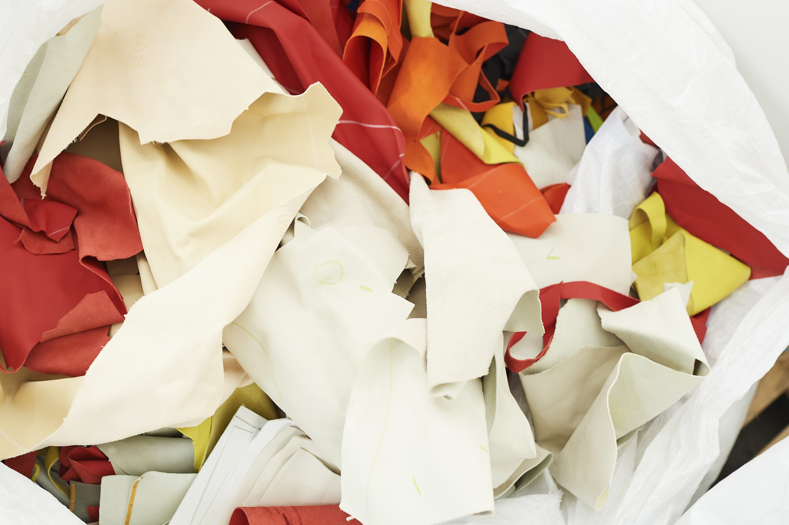 Lamborghini'S Upcycled Leather Project Turns Supercar Factory Scraps Into Covetable Accessories 5 White bag filled with colorful reclaimed leather scraps in red, orange, yellow, and cream from lamborghini production