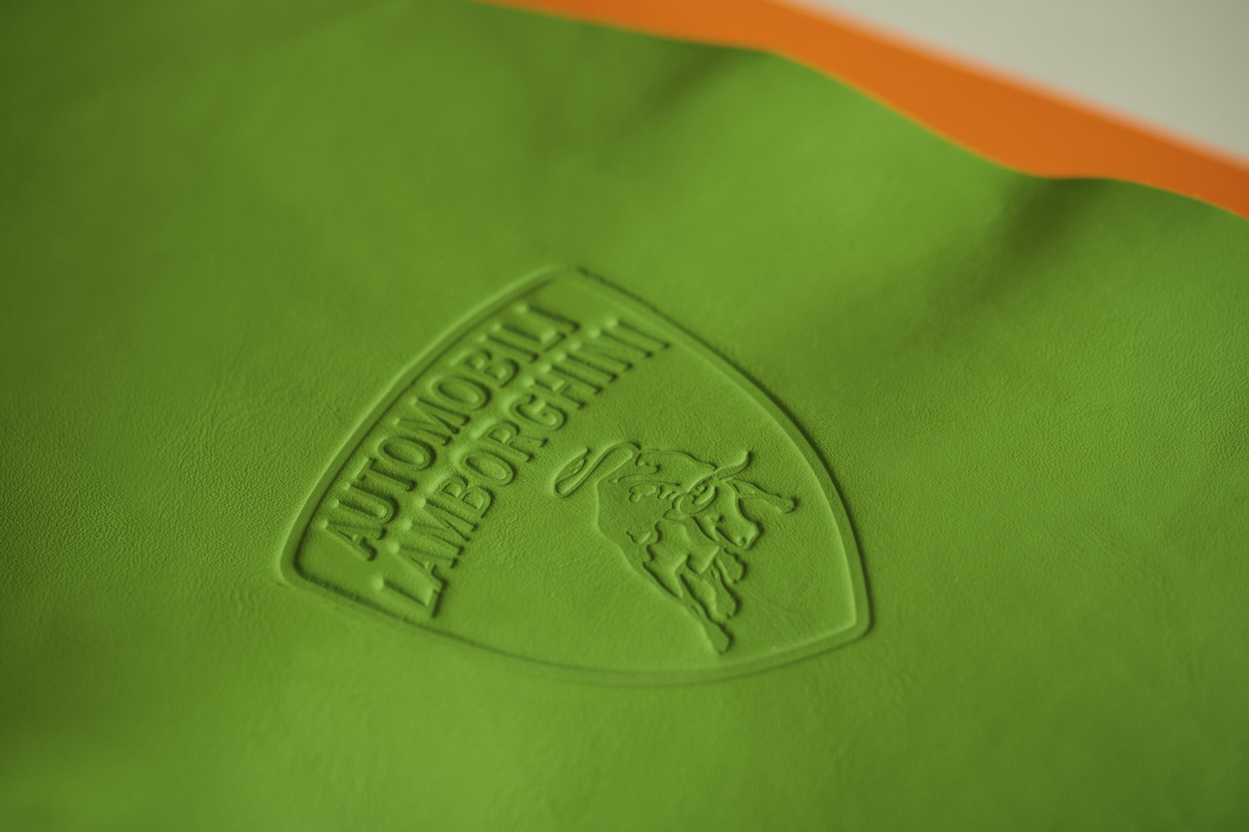 Lamborghini'S Upcycled Leather Project Turns Supercar Factory Scraps Into Covetable Accessories 13 Close-up of the automobili lamborghini shield logo embossed on vibrant green leather