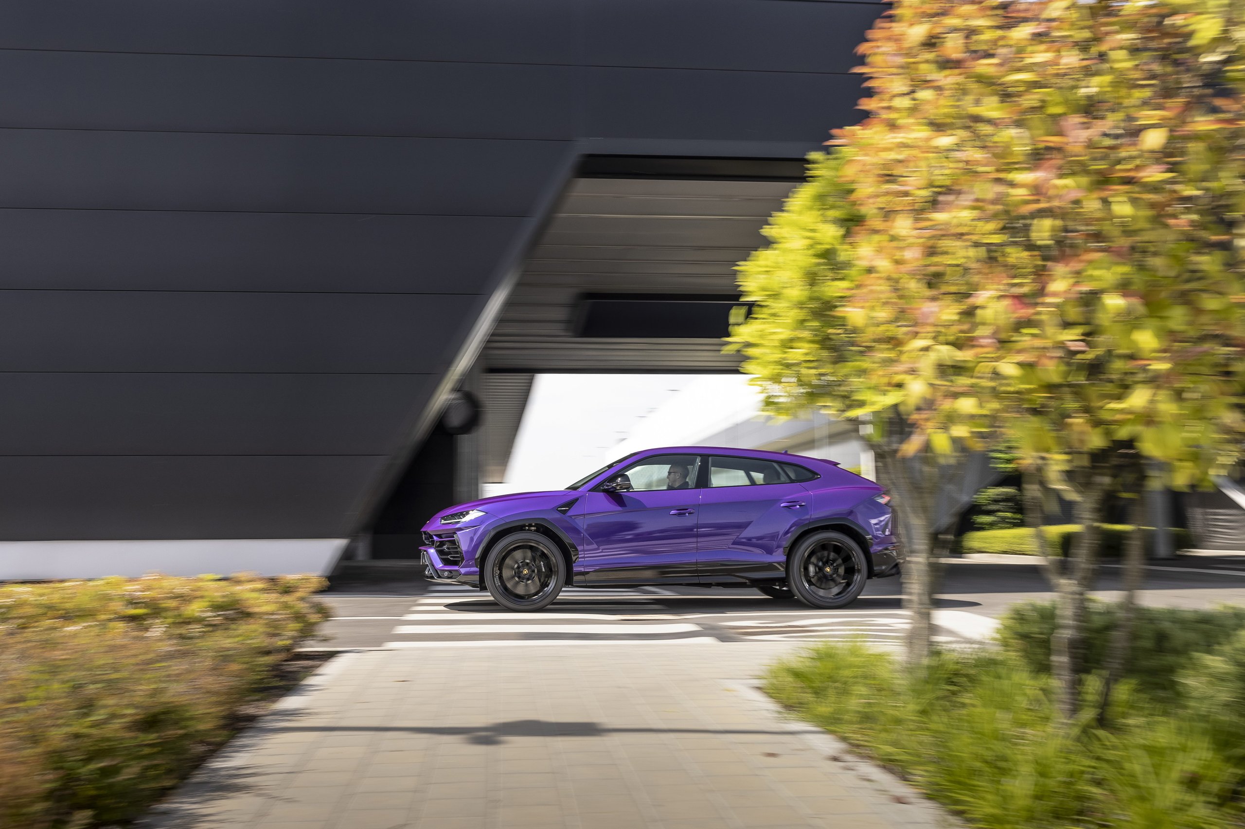 20,000 Urus Units In Four Years: How Lamborghini'S Bestseller Doubled The Entire Company 7 Purple lamborghini urus in motion past a modern building, conveying speed and dynamism